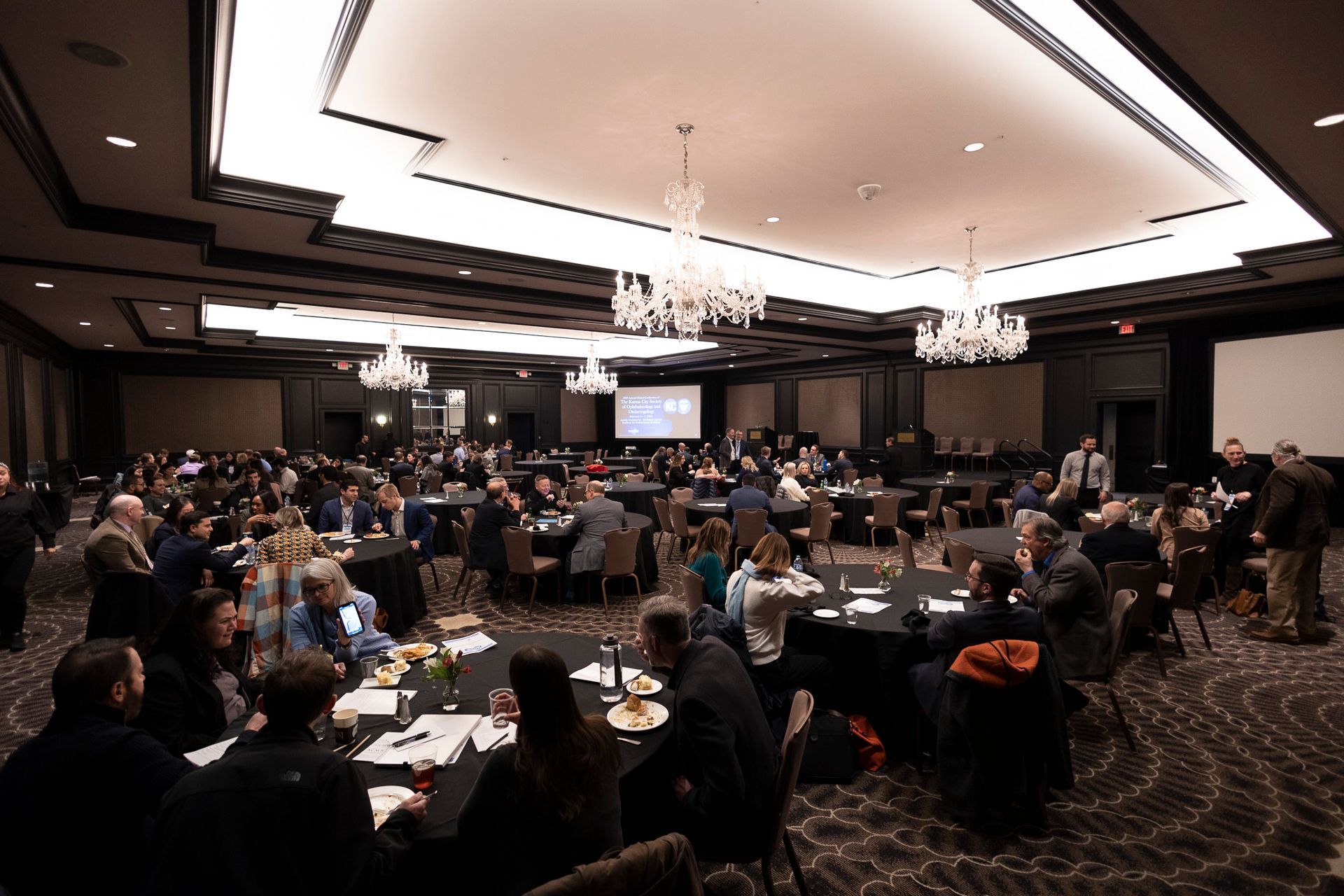 A large room filled with people sitting at tables.