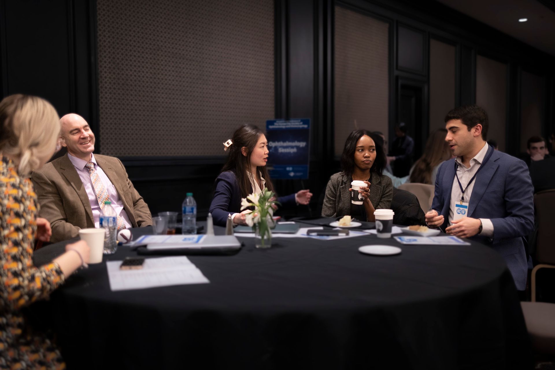 A group of people are sitting around a table having a conversation.