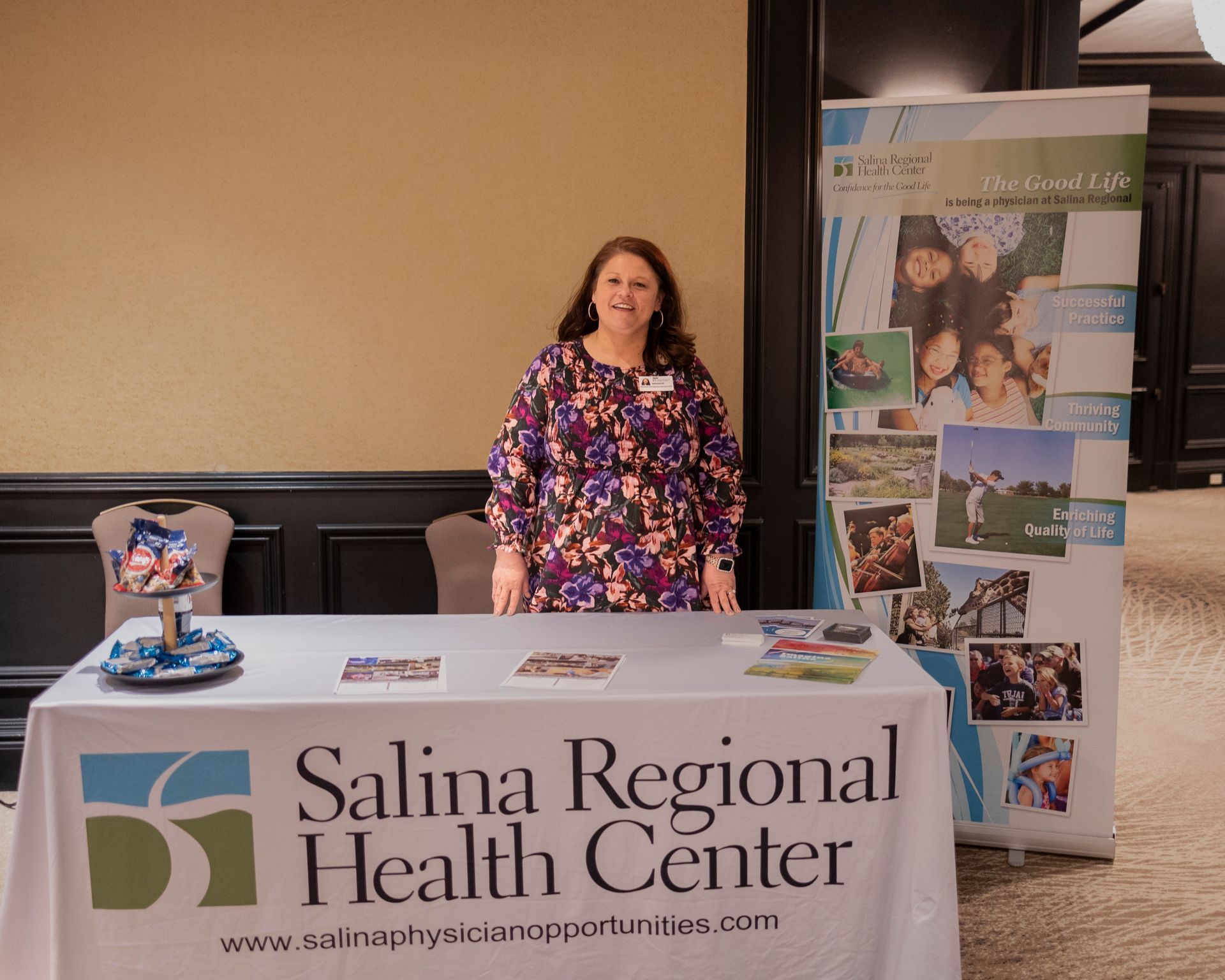 A woman stands behind a table that says salina regional health center
