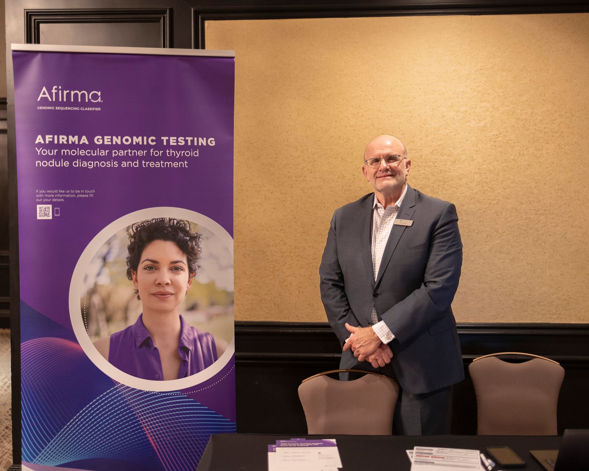 A man in a suit stands in front of a sign that says firma