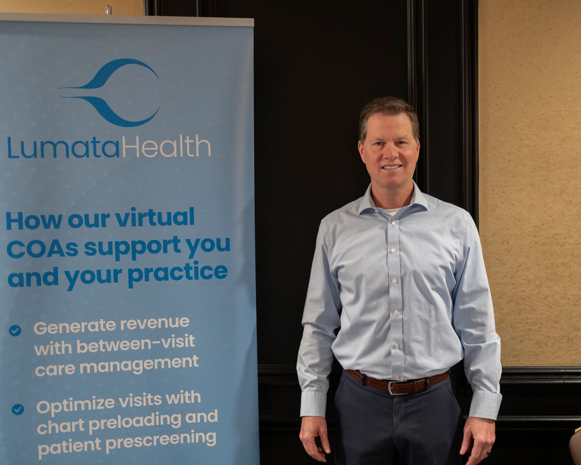 A man stands in front of a lumata health banner