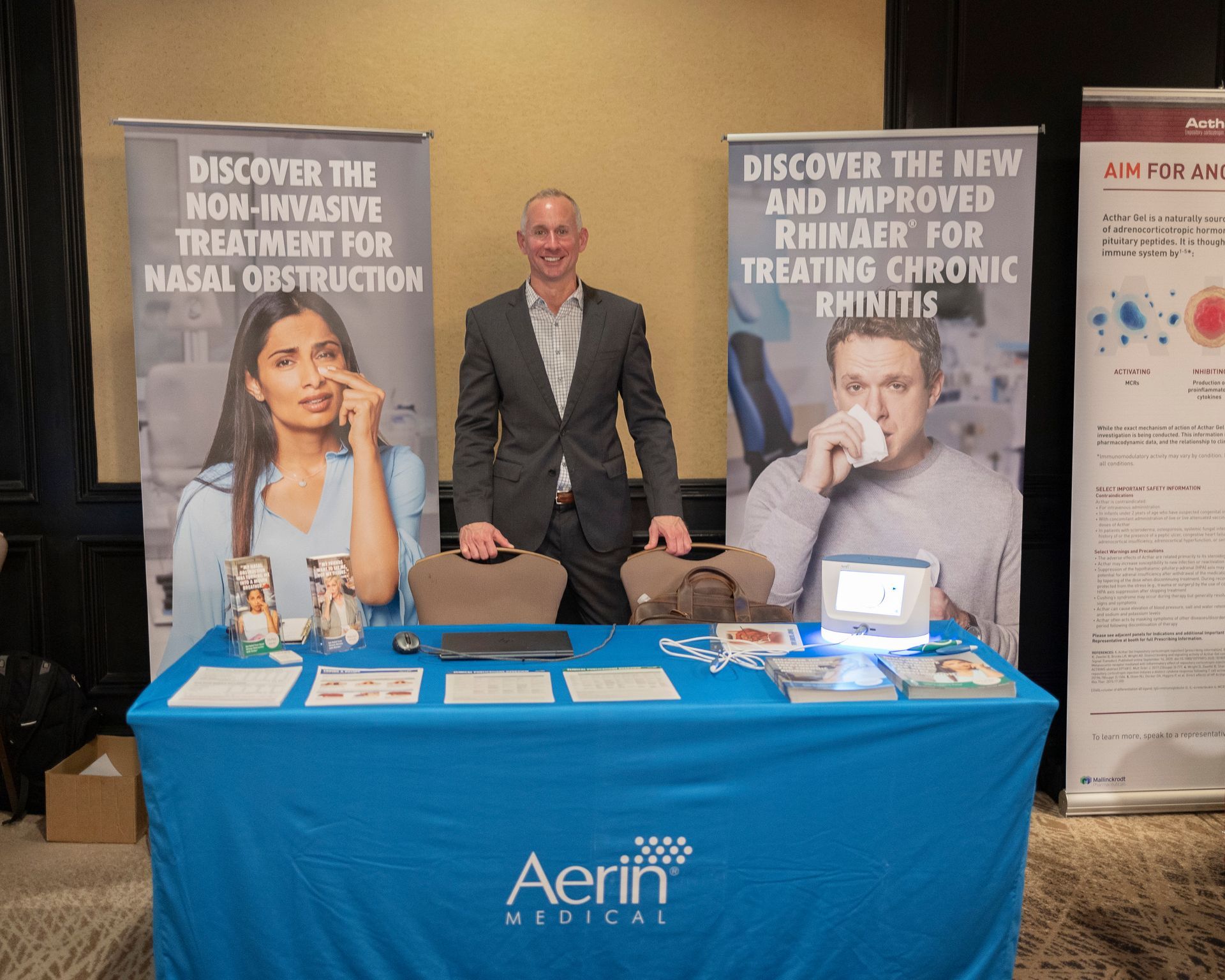 A man in a suit is standing in front of a table with a blue table cloth.
