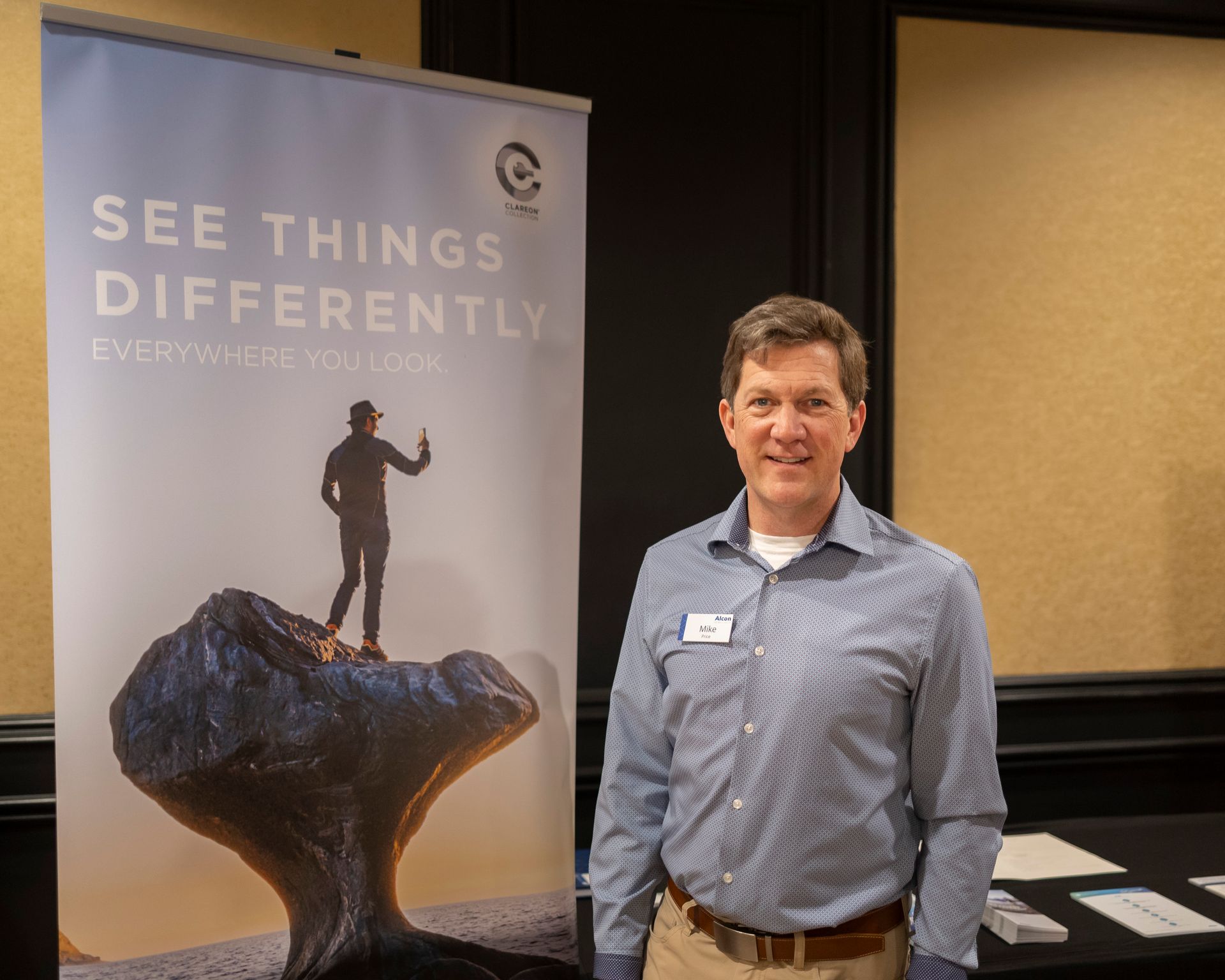 A man is standing in front of a sign that says see things differently