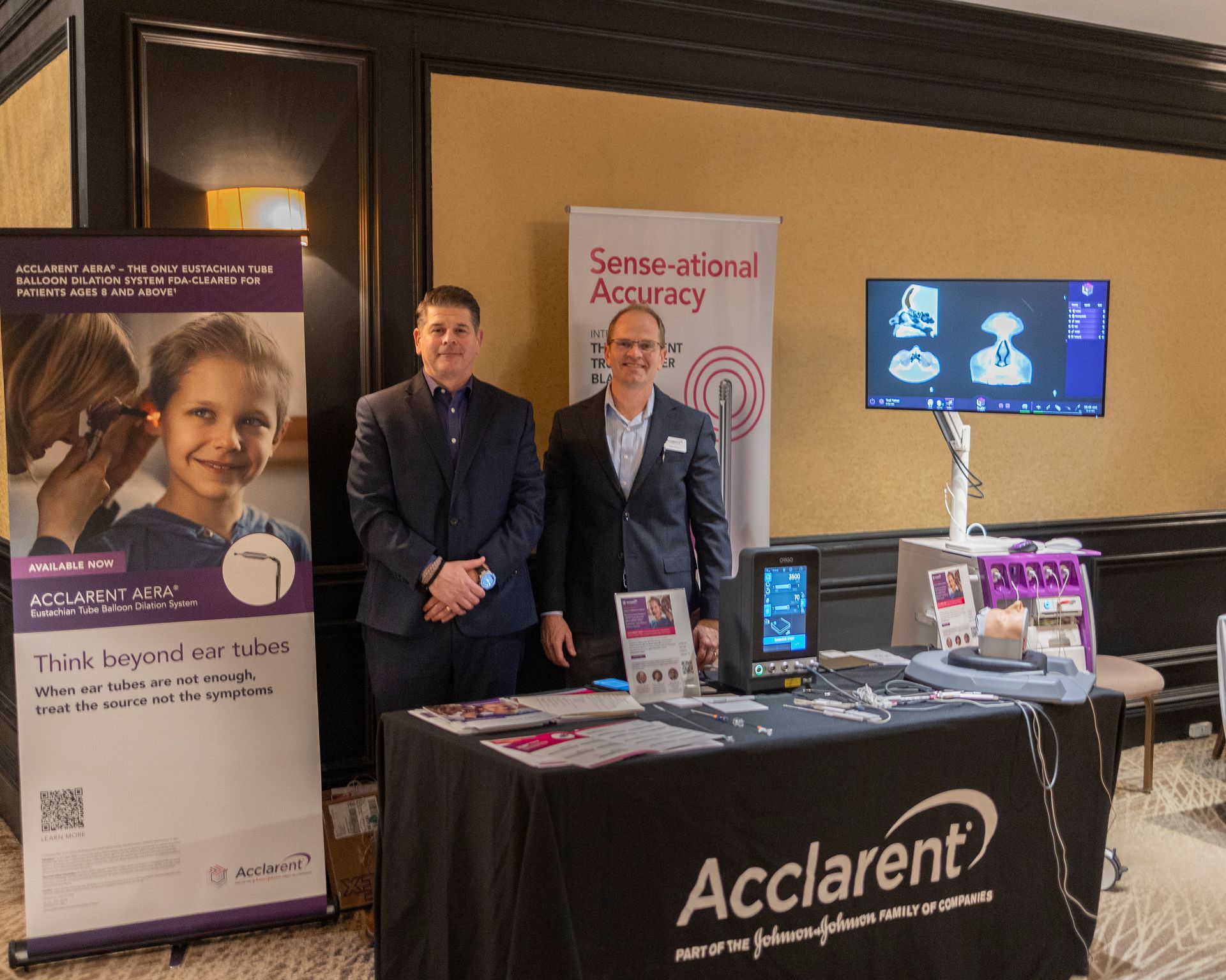 Two men standing in front of a table that says acclarent