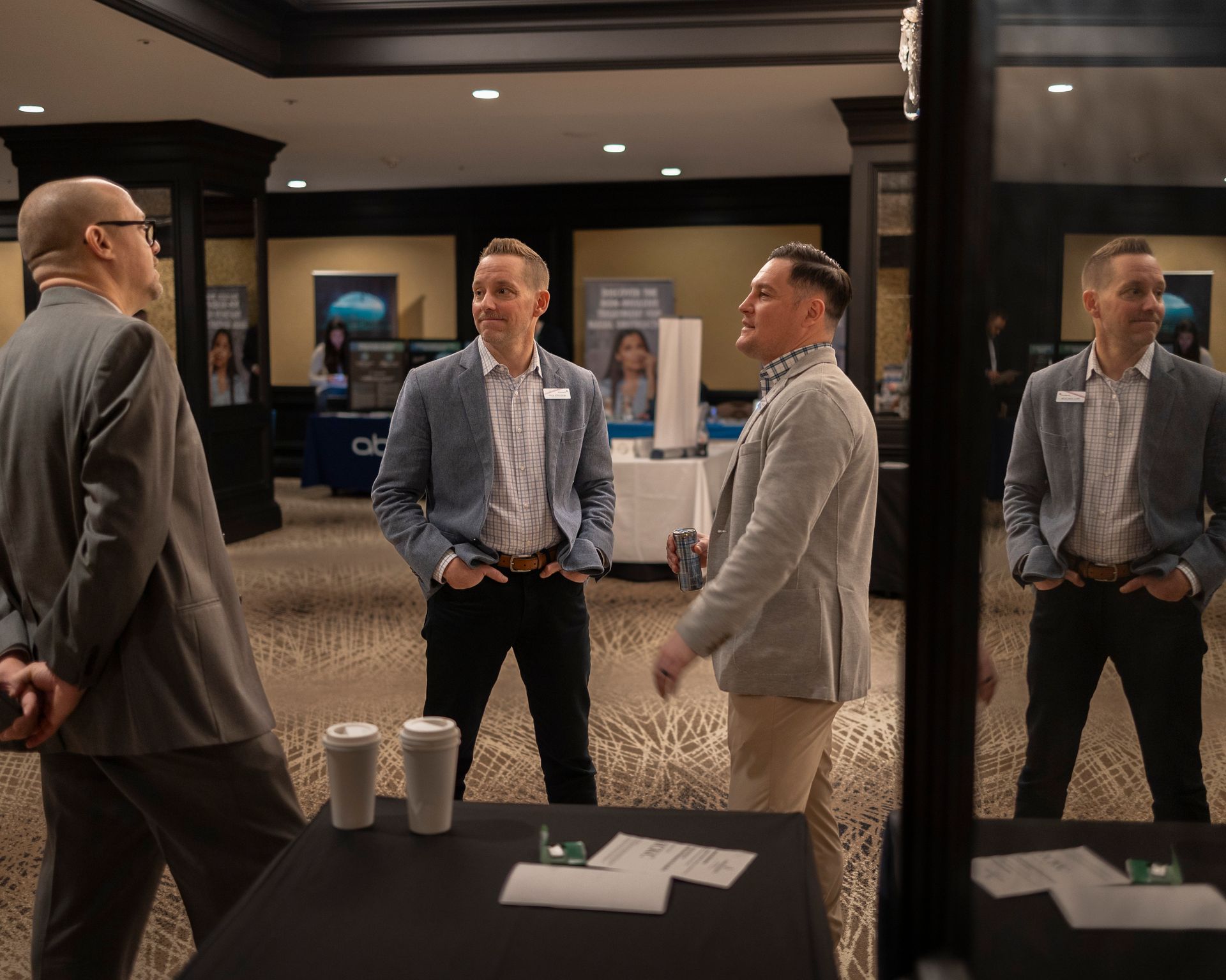 A group of men are standing around a table talking to each other.
