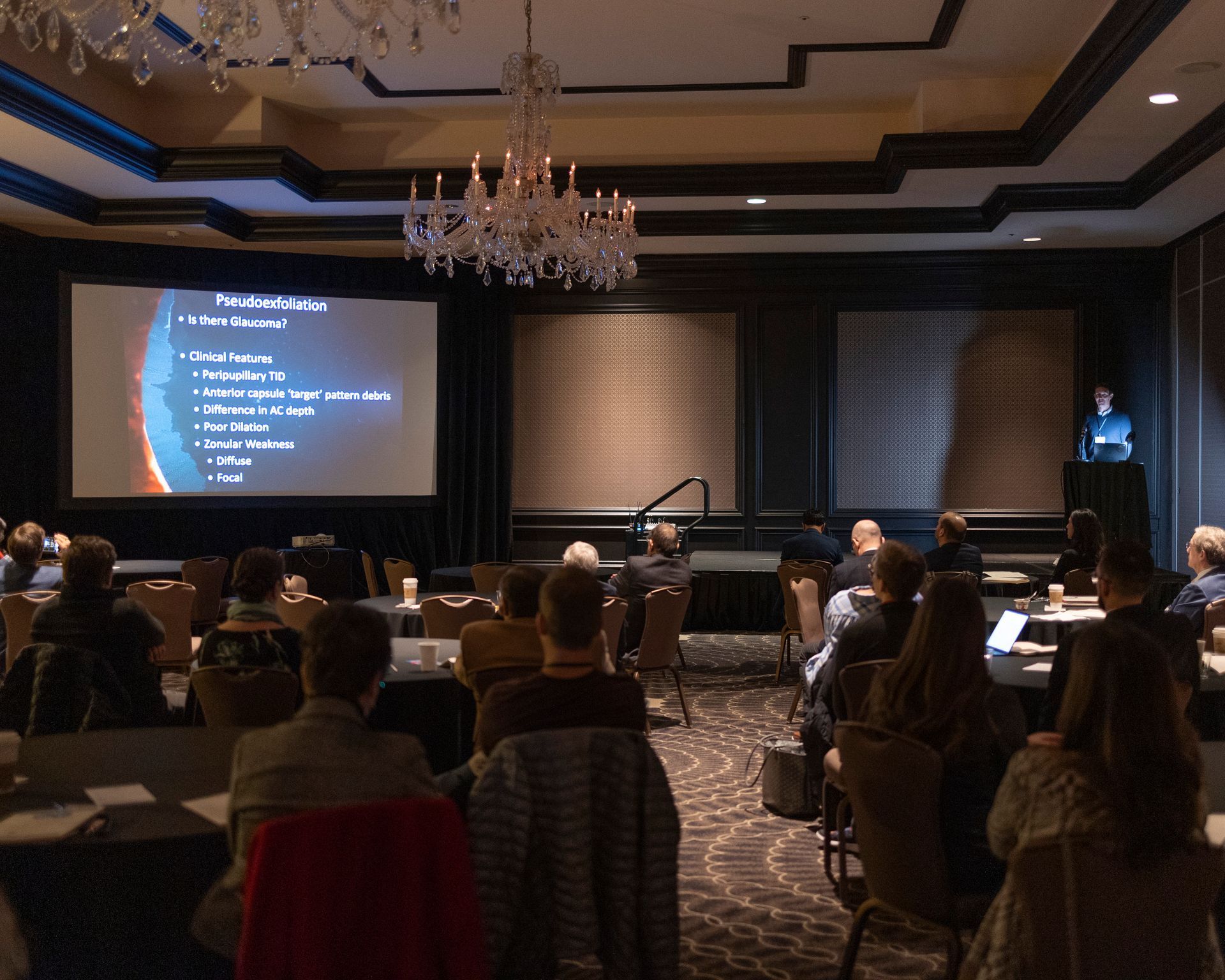 A group of people are sitting in front of a large screen with a presentation on it