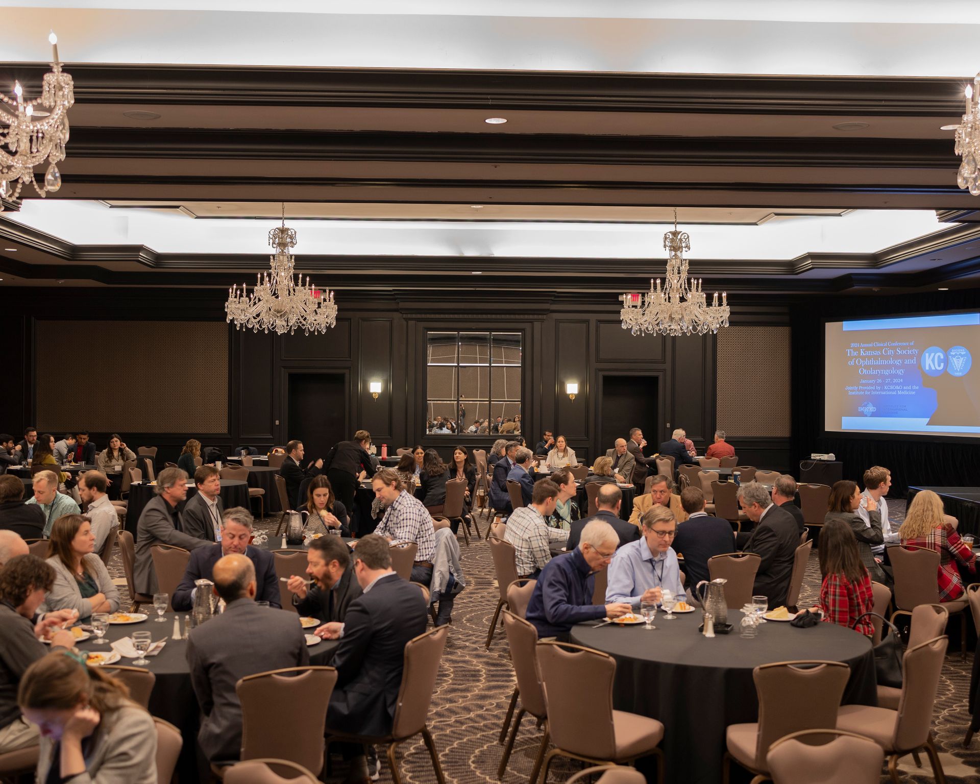 A large room filled with people sitting at tables and chairs.