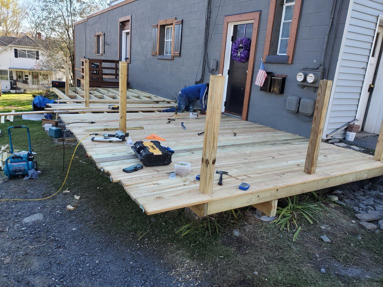 Construction workers building a wooden deck attached to a gray building.