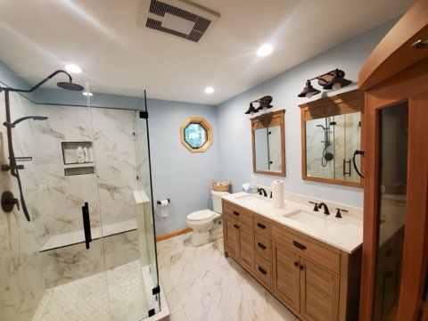 Bathroom with a large shower, double vanity, blue walls, and light tile.