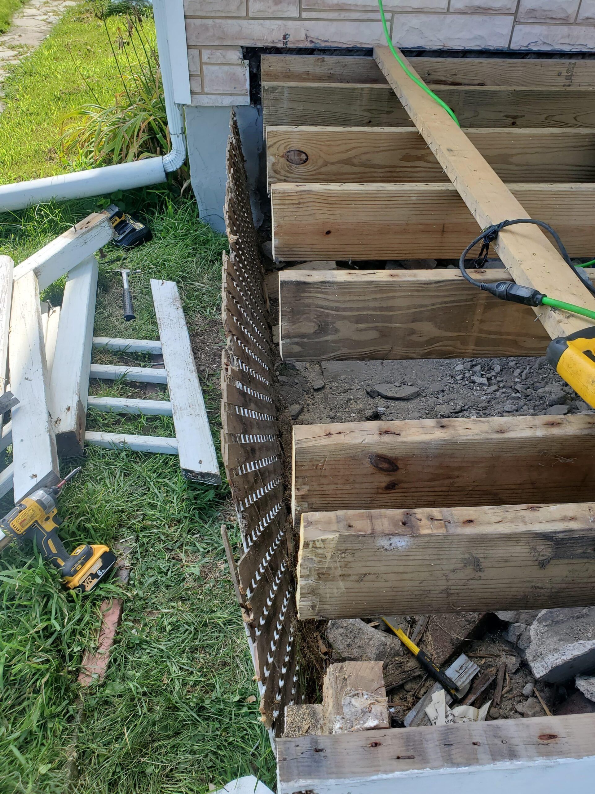 Construction site: partially built wooden steps and deck beside a white picket fence