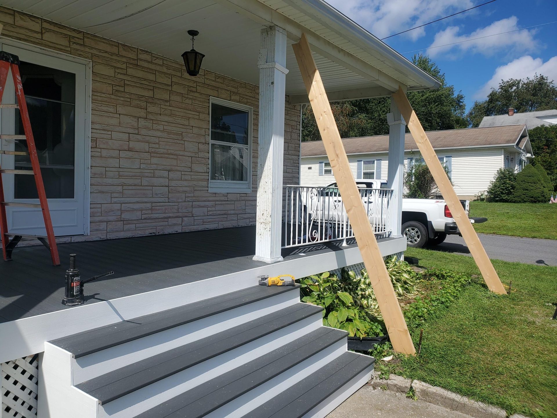 Wooden beams supporting a porch roof during a renovation, steps lead to the porch.