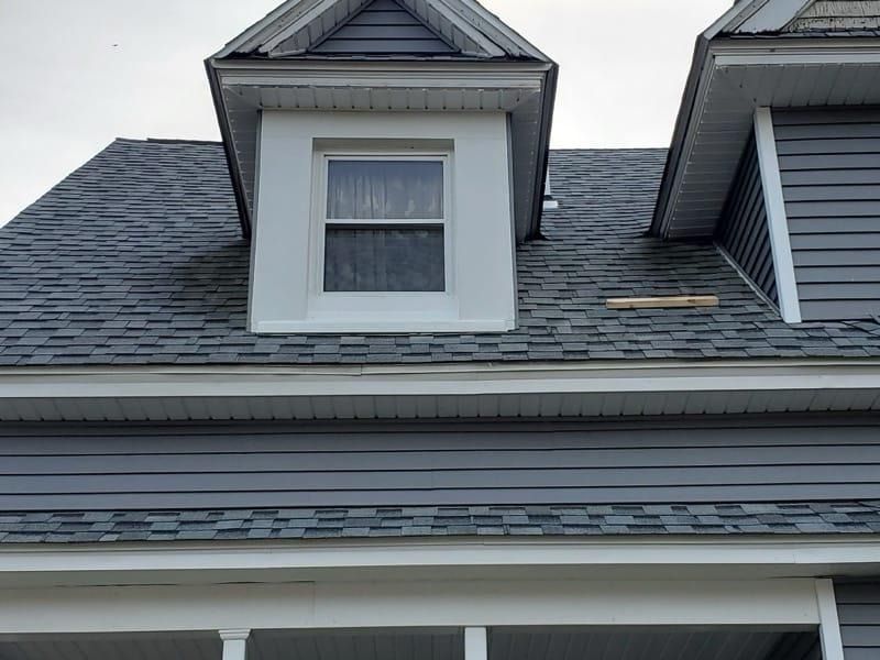 Gray house with a dormer window, gray shingles, and siding. White trim.