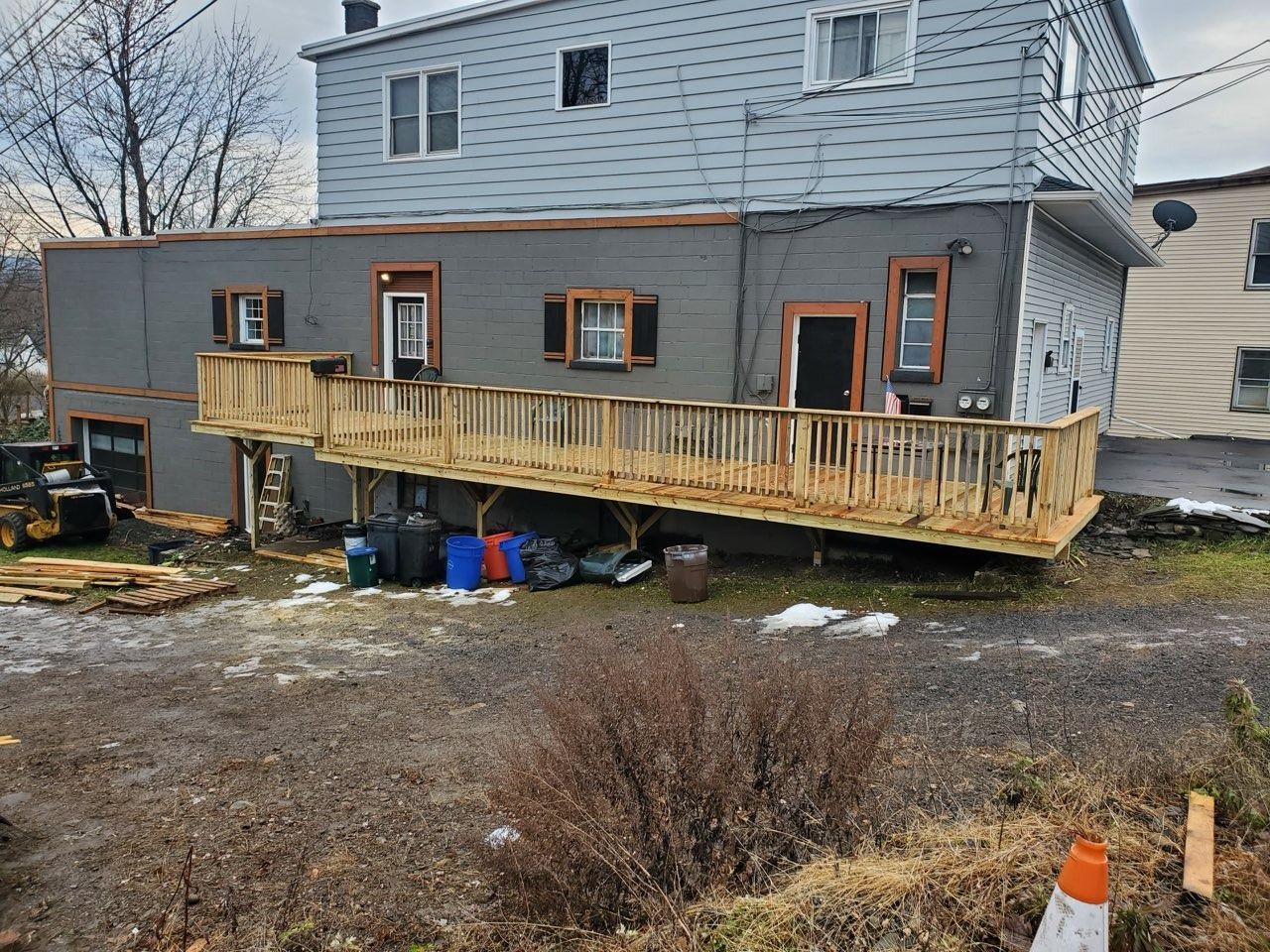Back view of a two-story building with a wooden deck. The deck has a significant slope.