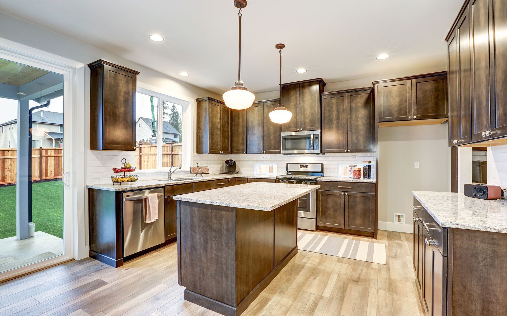 Kitchen with dark brown cabinets, light countertops, and wooden floors.
