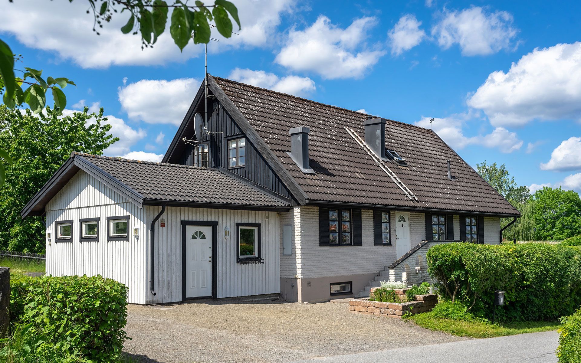 Two-story house with white and gray exterior, dark roof, and blue sky.