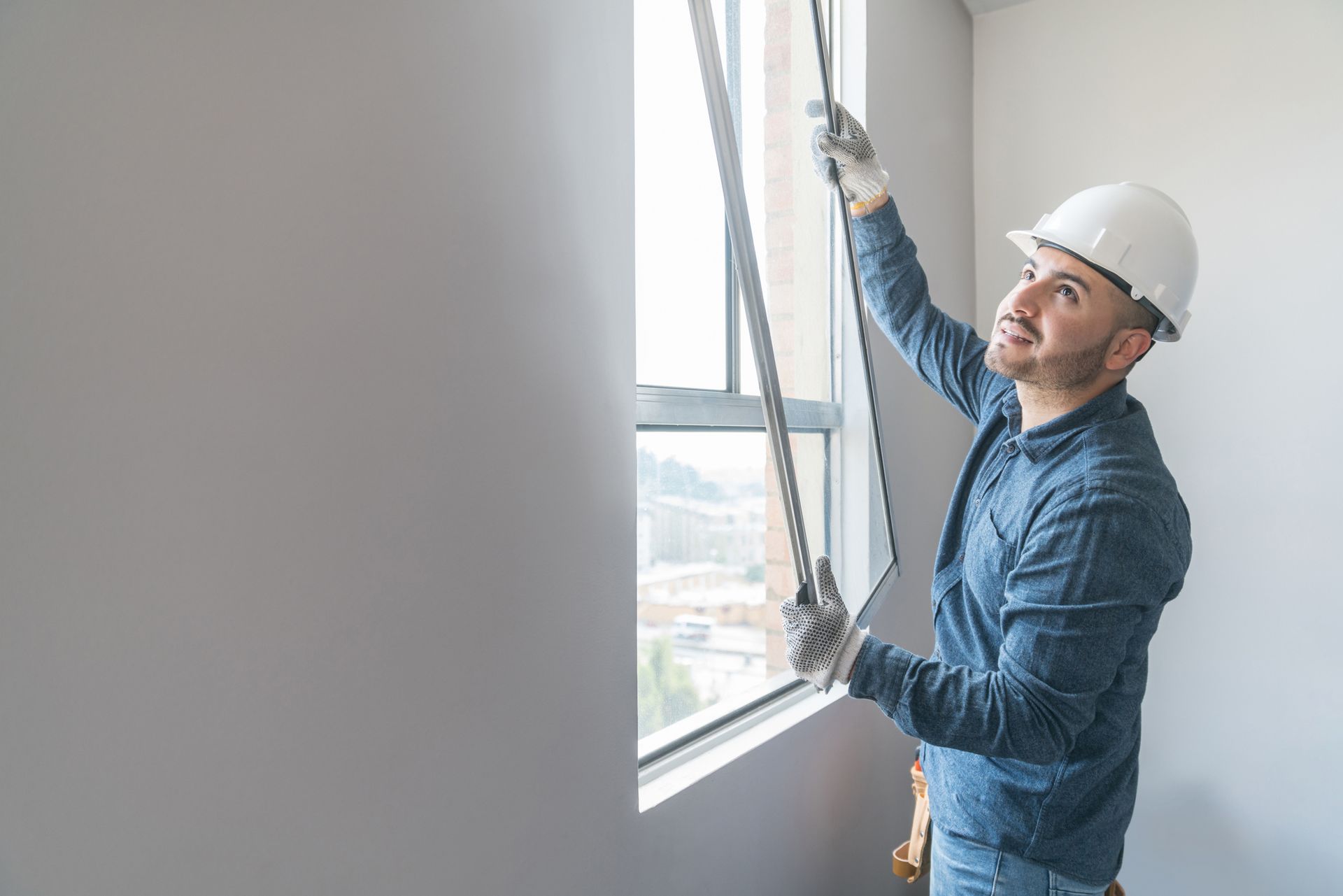 A man is installing a window in a room.