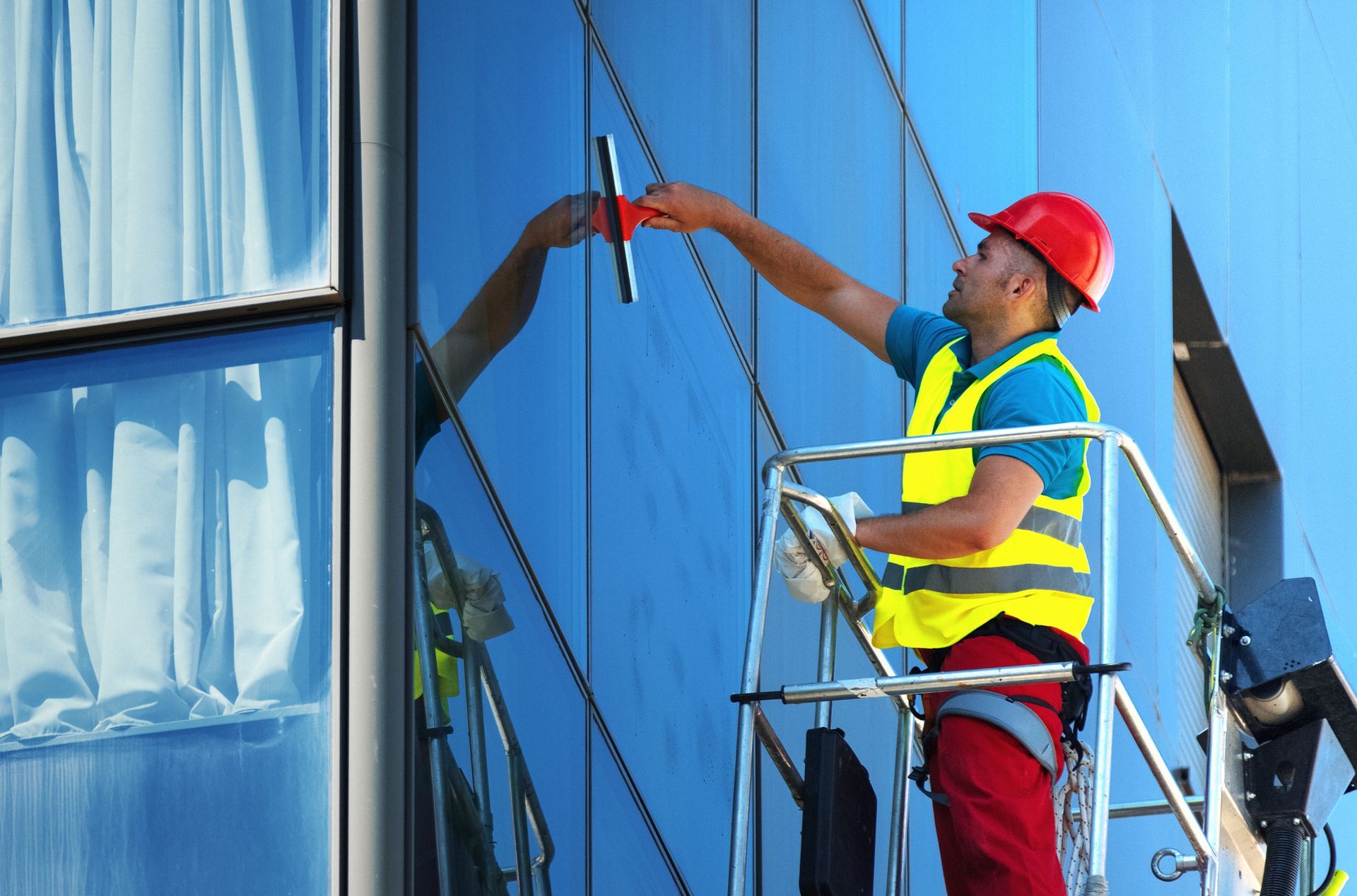 A man is standing on a ladder cleaning a window on a building.