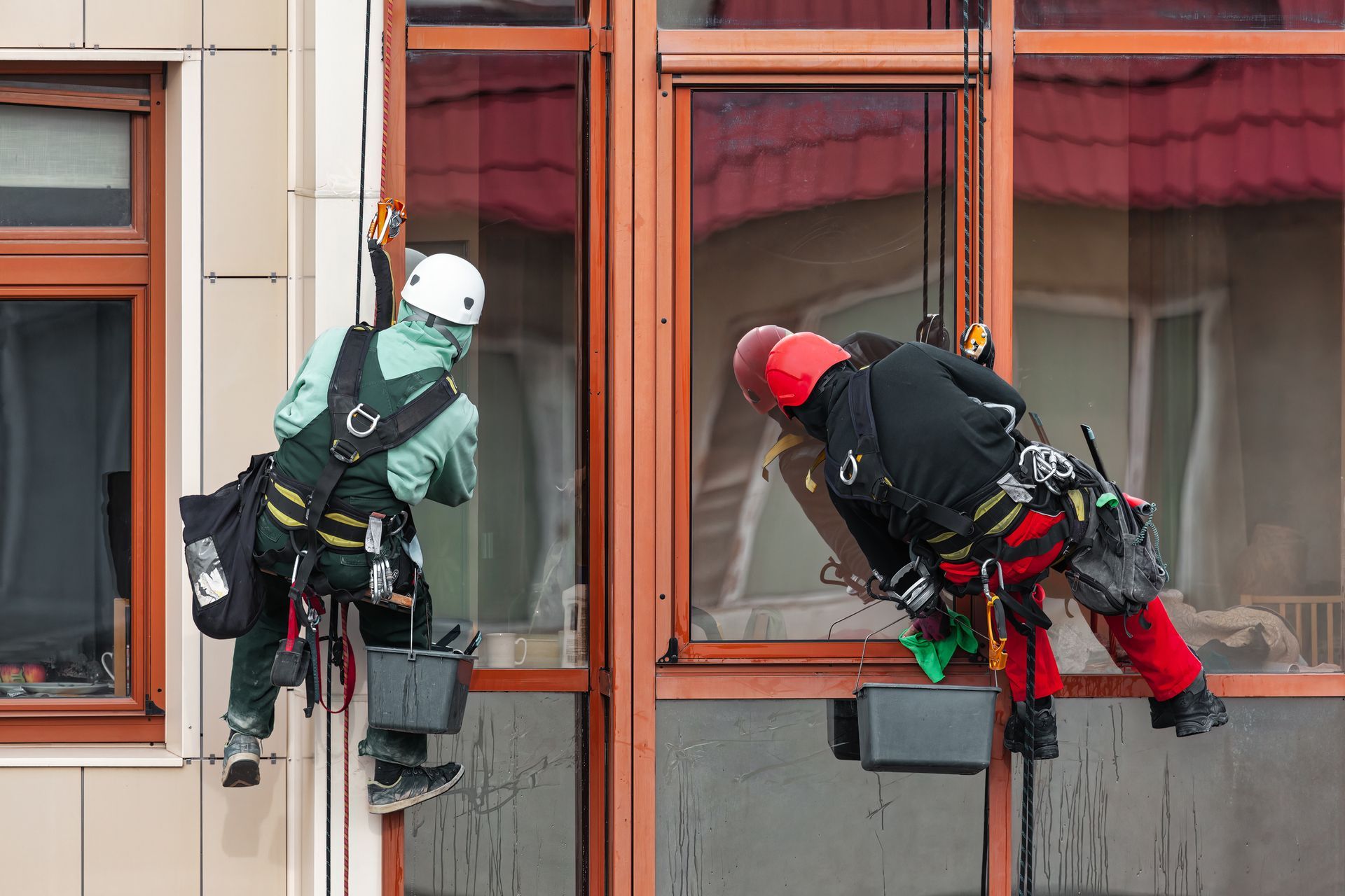 Workers washing windows at exterior building, showcasing expert mirror and window cleaning.