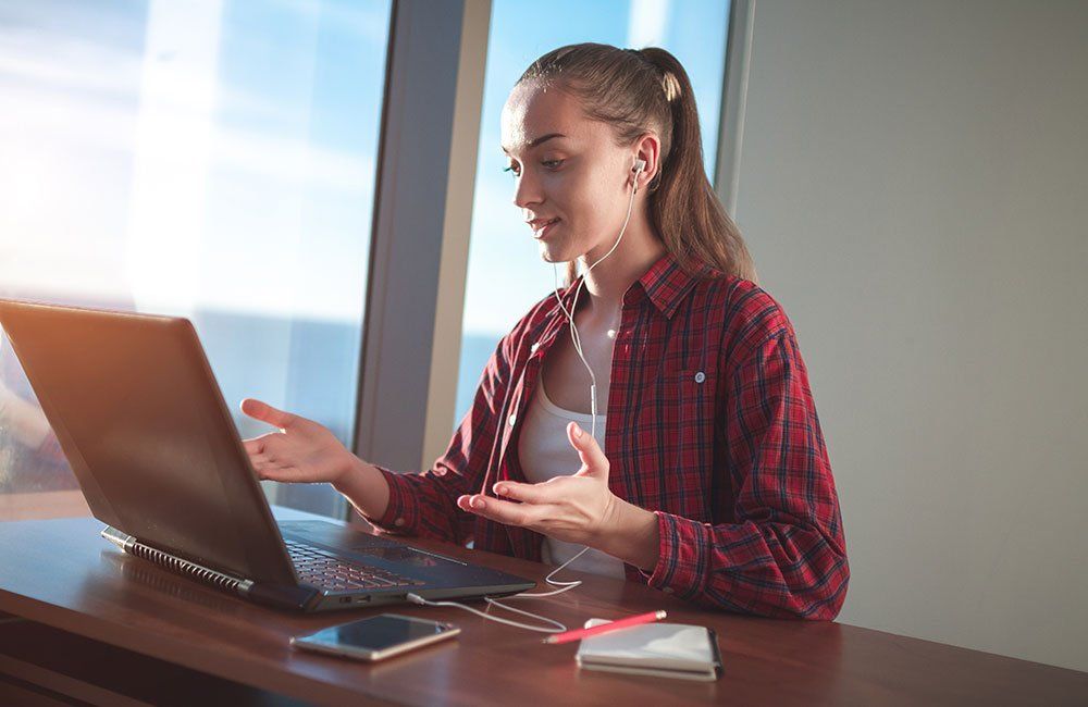 A woman is sitting at a desk using a laptop computer.