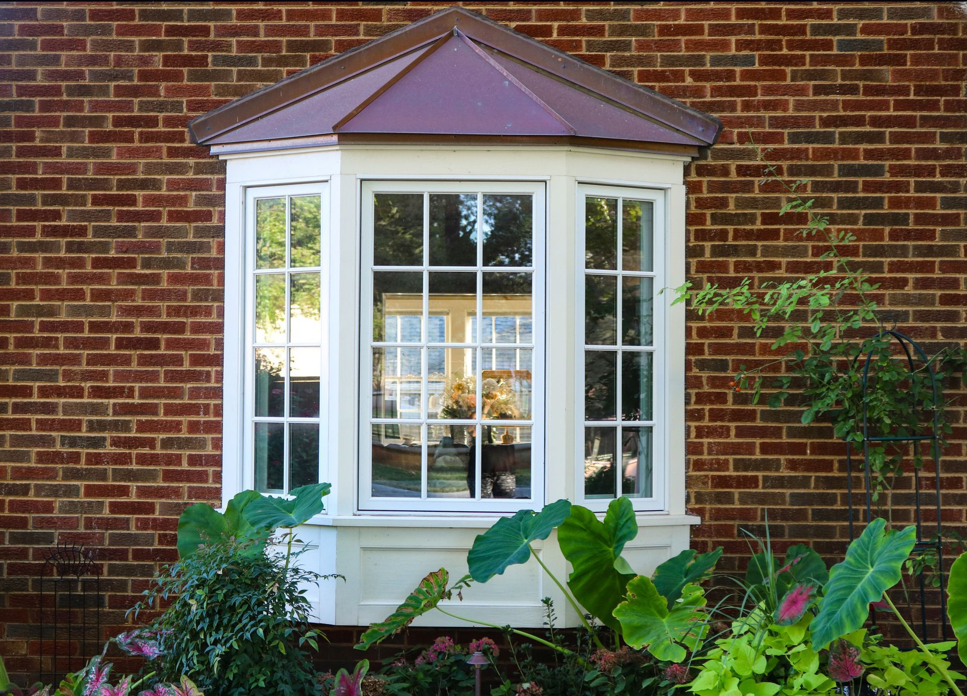 A bay window on a brick building with a copper roof