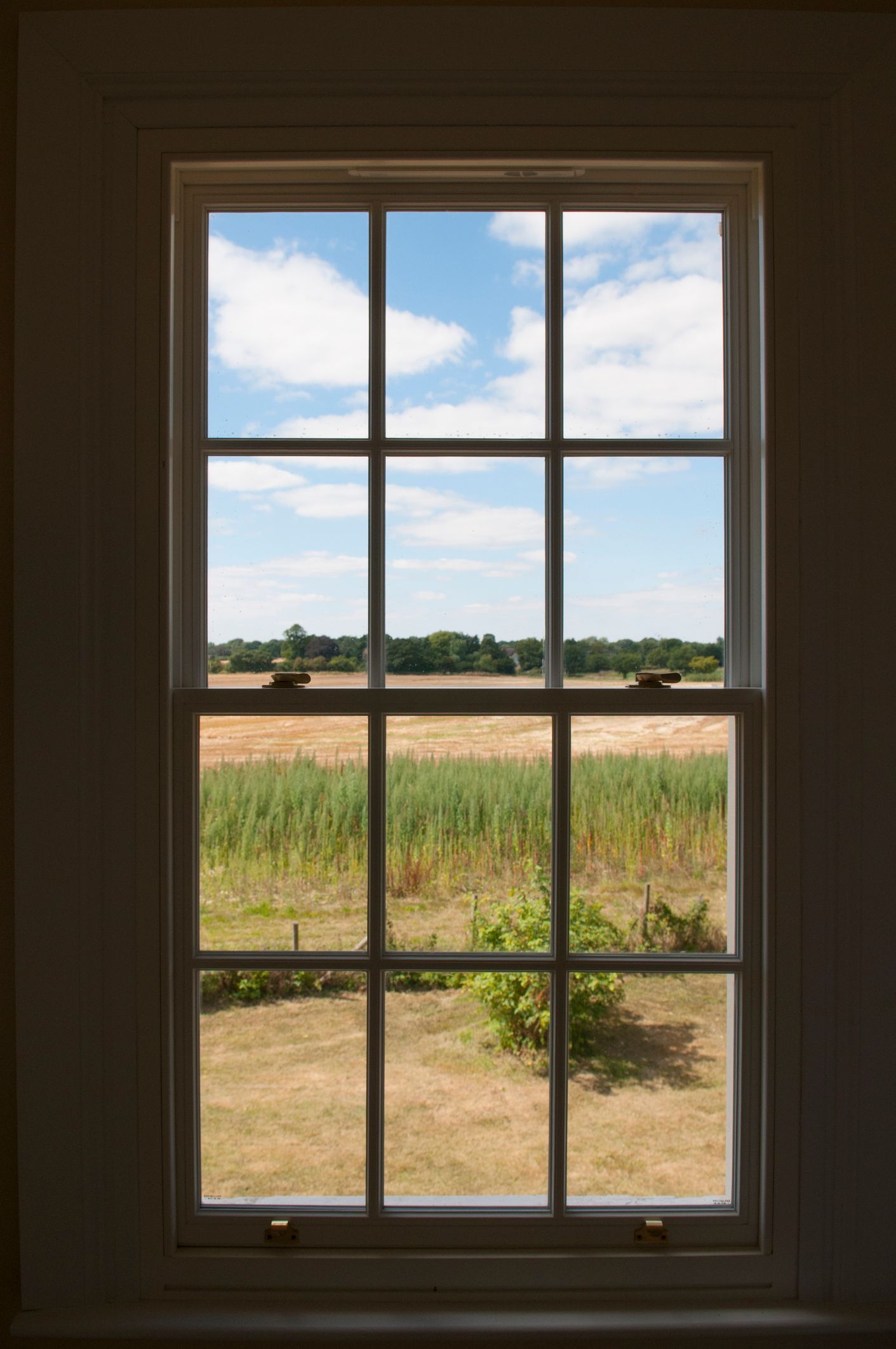 A window with a view of a field and a blue sky