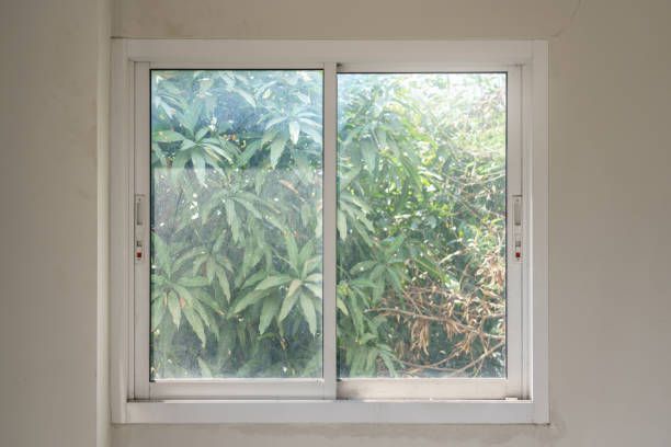 A sliding glass window with a view of trees in a room.