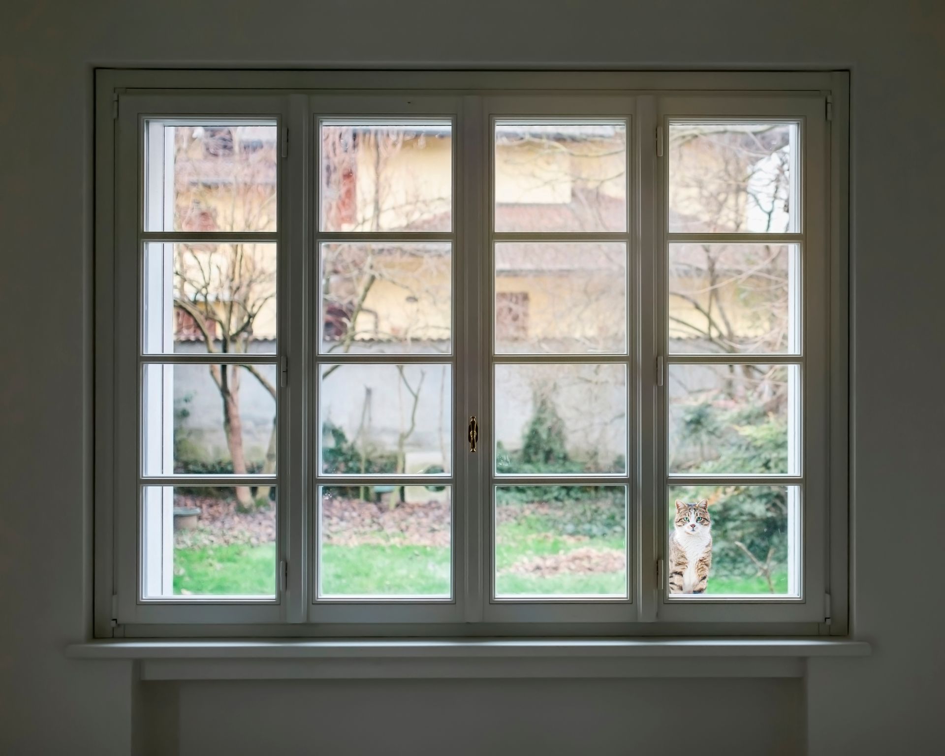 An empty room with a window looking out to a garden.
