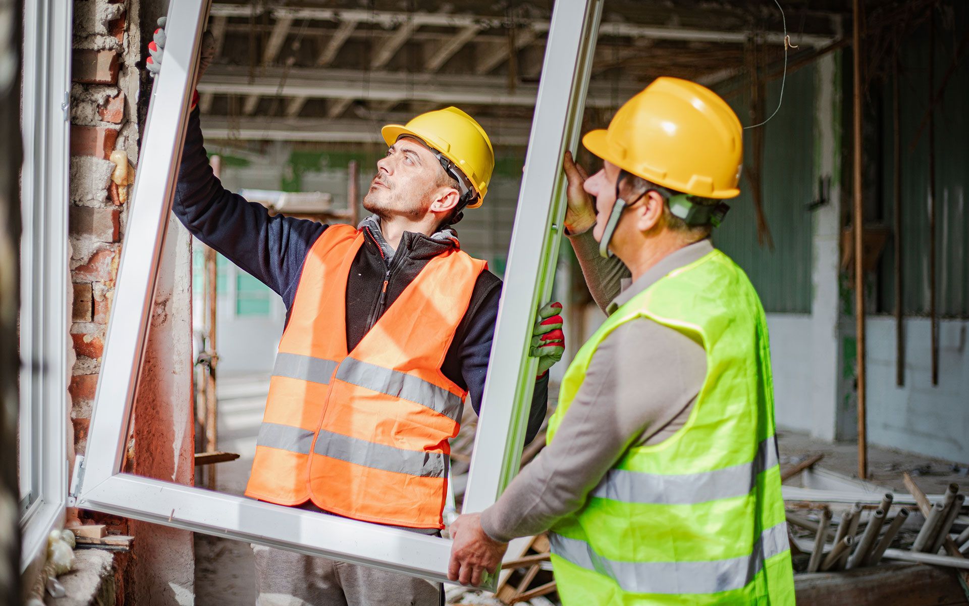 Two workers installing a vinyl window in a construction 