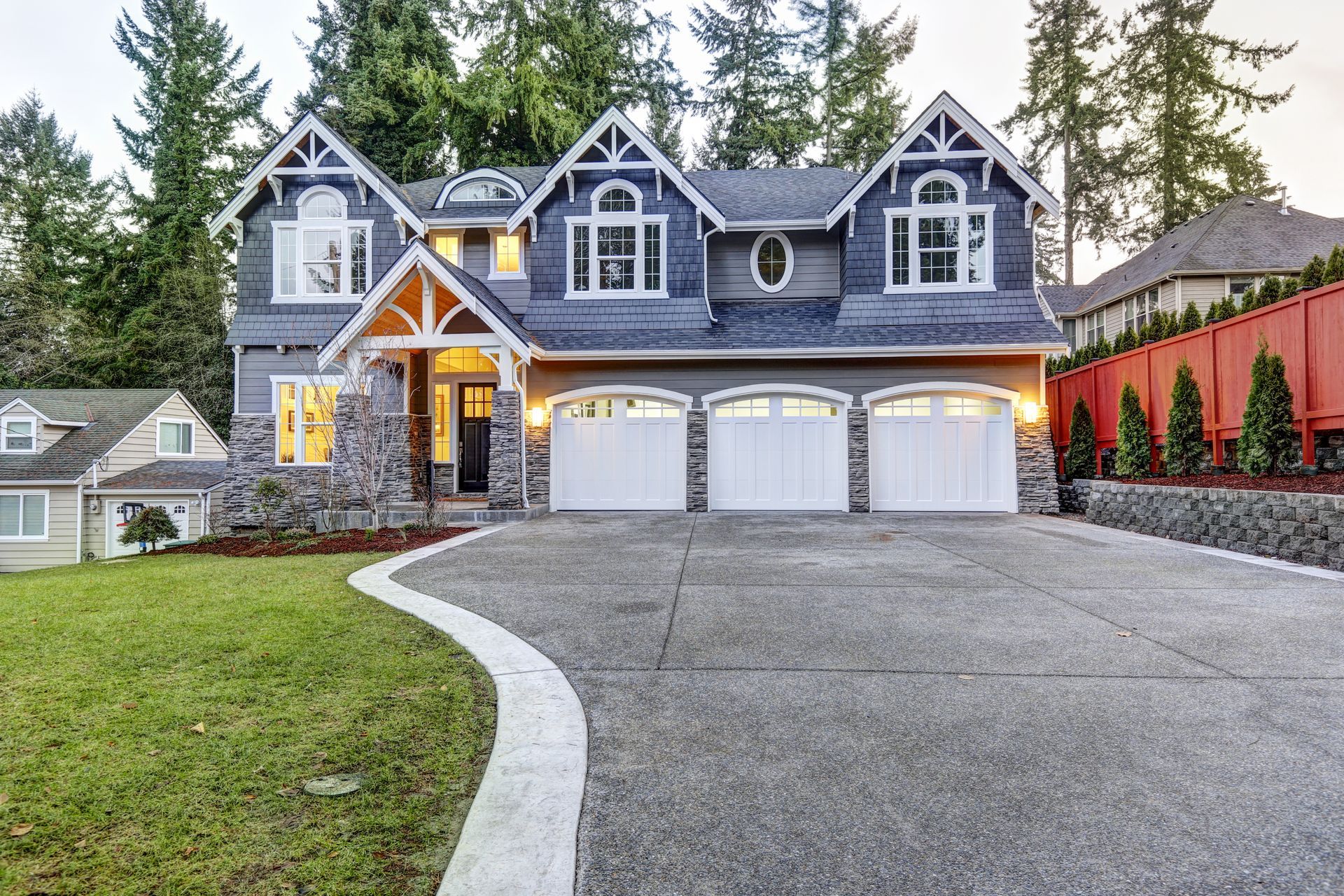 A large house with three garage doors and a curved driveway.