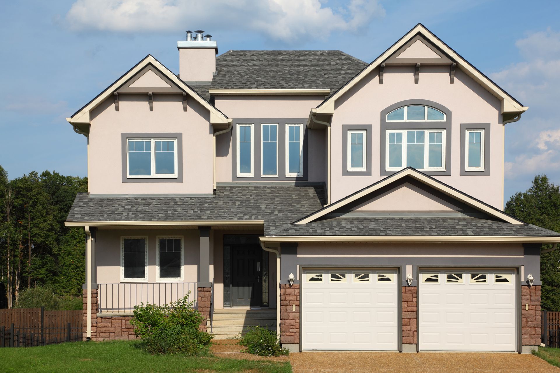 A large house with a gray roof and white garage doors