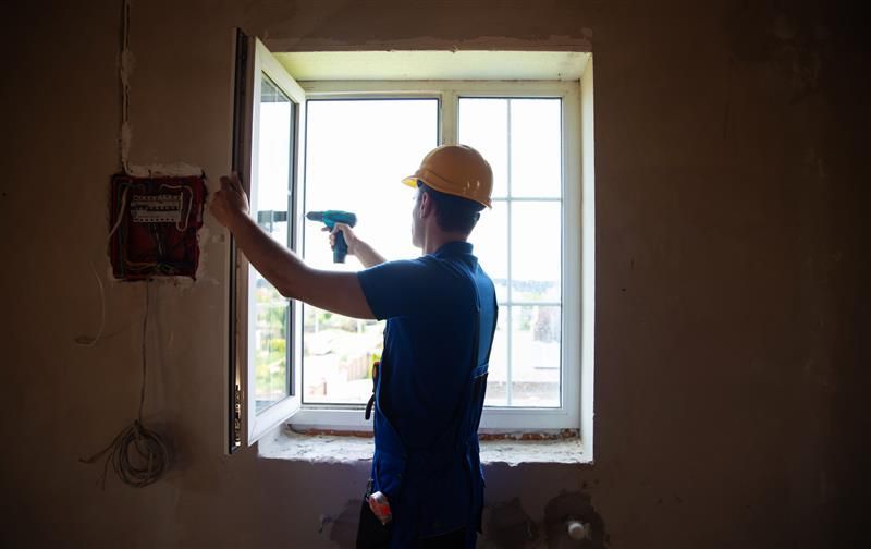 A man is wrapping up the replacement of a window.