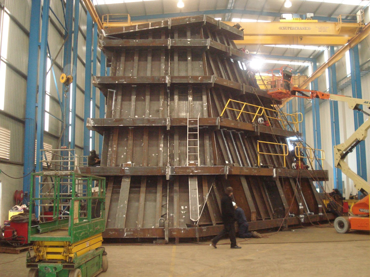 A large metal structure is being built in a factory