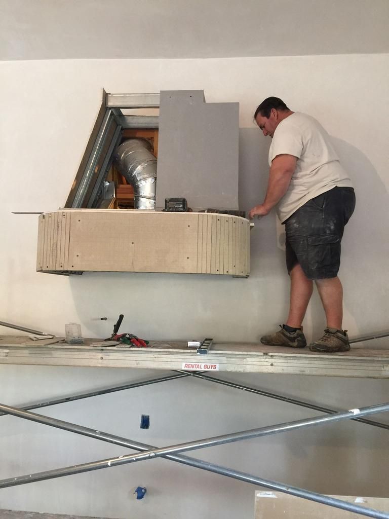 A man is standing on a platform working on a wall.