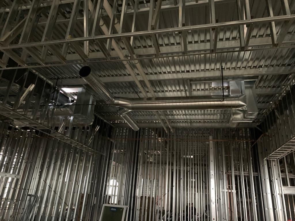 A building under construction with a lot of pipes coming out of the ceiling.