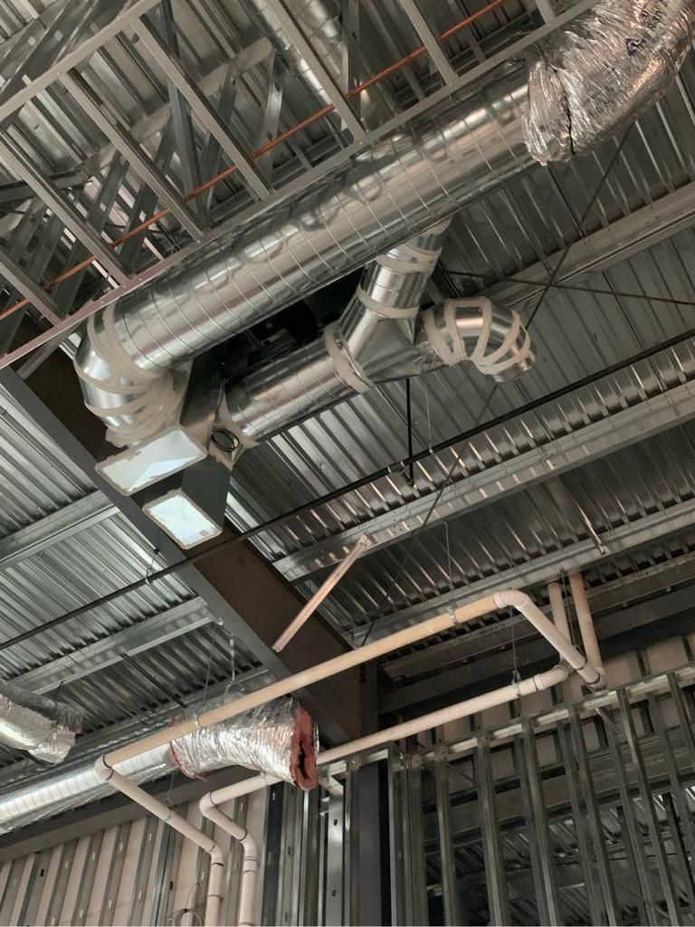 There are a lot of pipes hanging from the ceiling of a building.