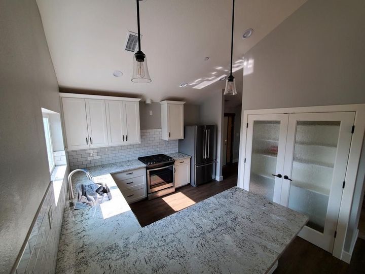 A kitchen with white cabinets , granite counter tops and stainless steel appliances.