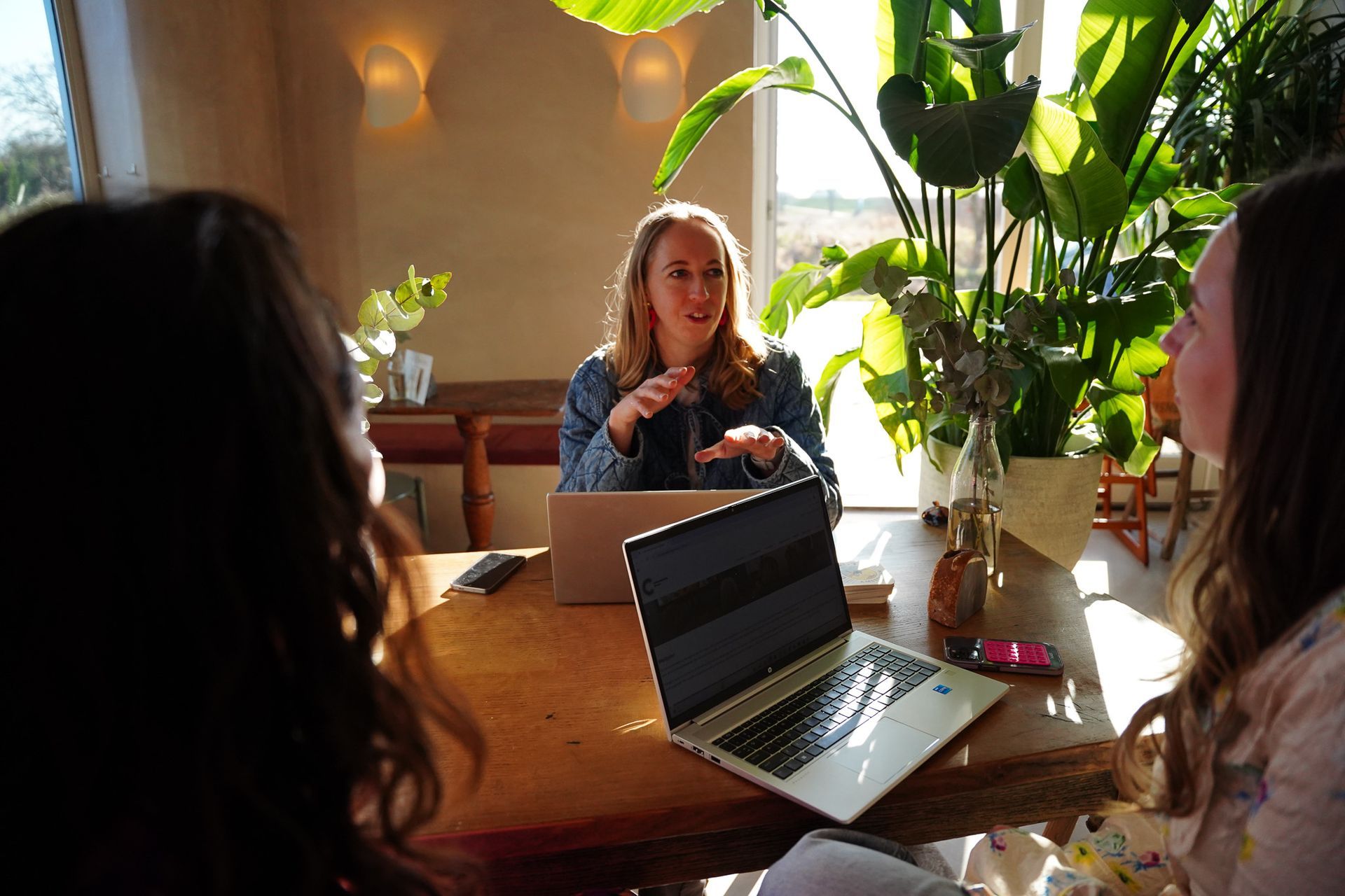 A group of women are sitting at a table with laptops.