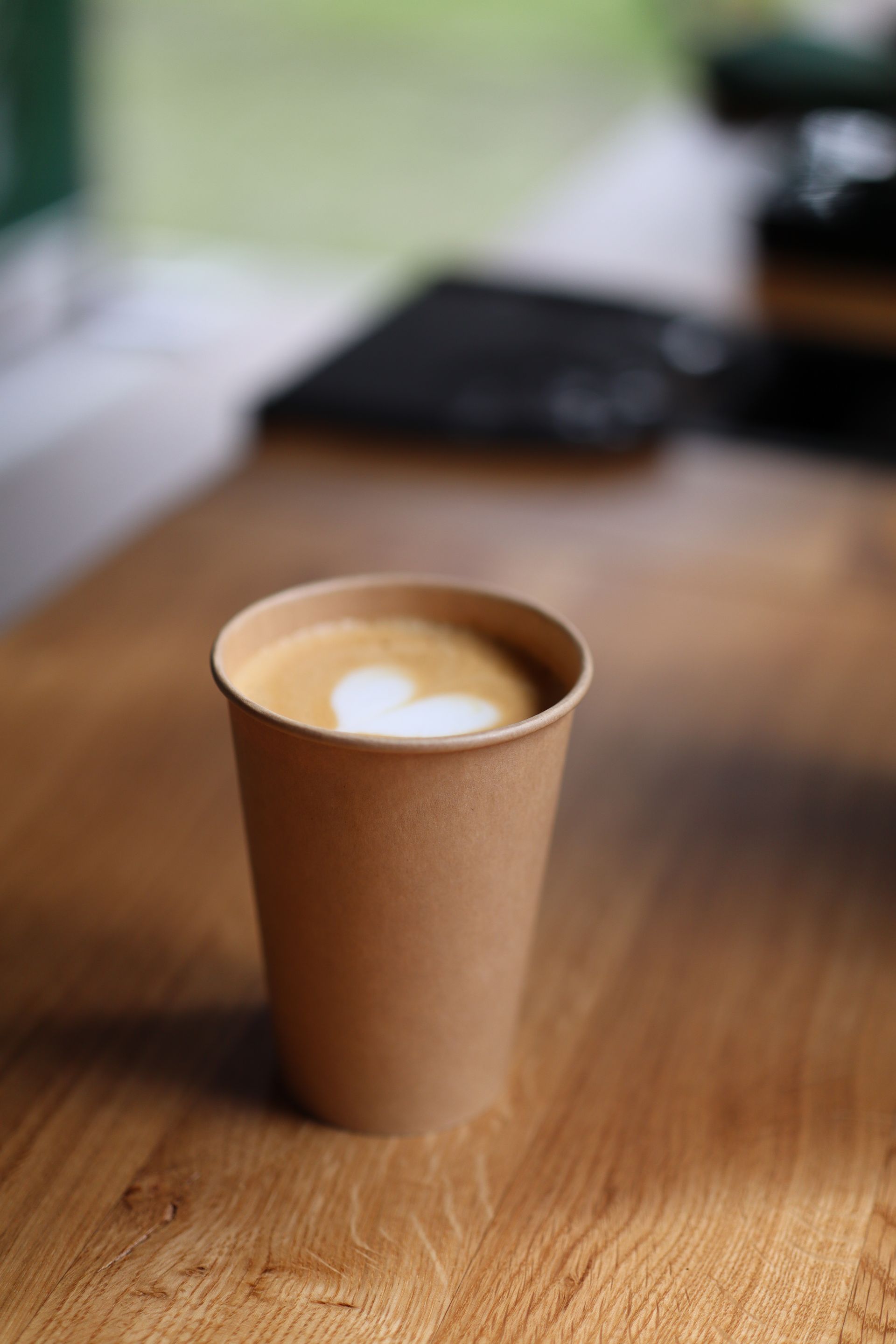A cup of coffee is sitting on a wooden table.