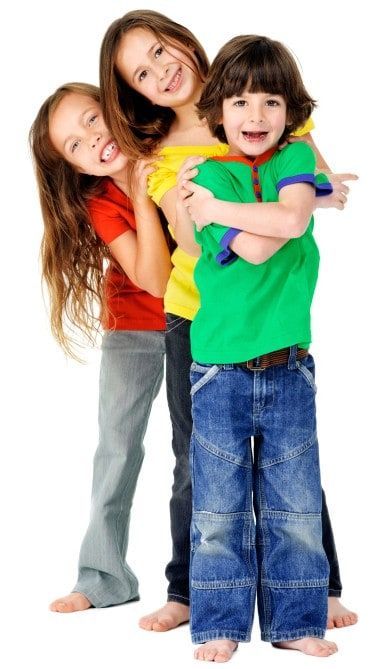 Three children in colorful shirts smiling and hugging.