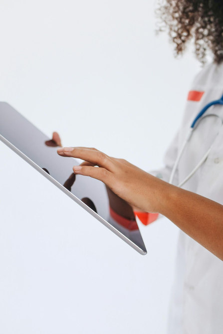 Doctor using a tablet, wearing a white coat and stethoscope.