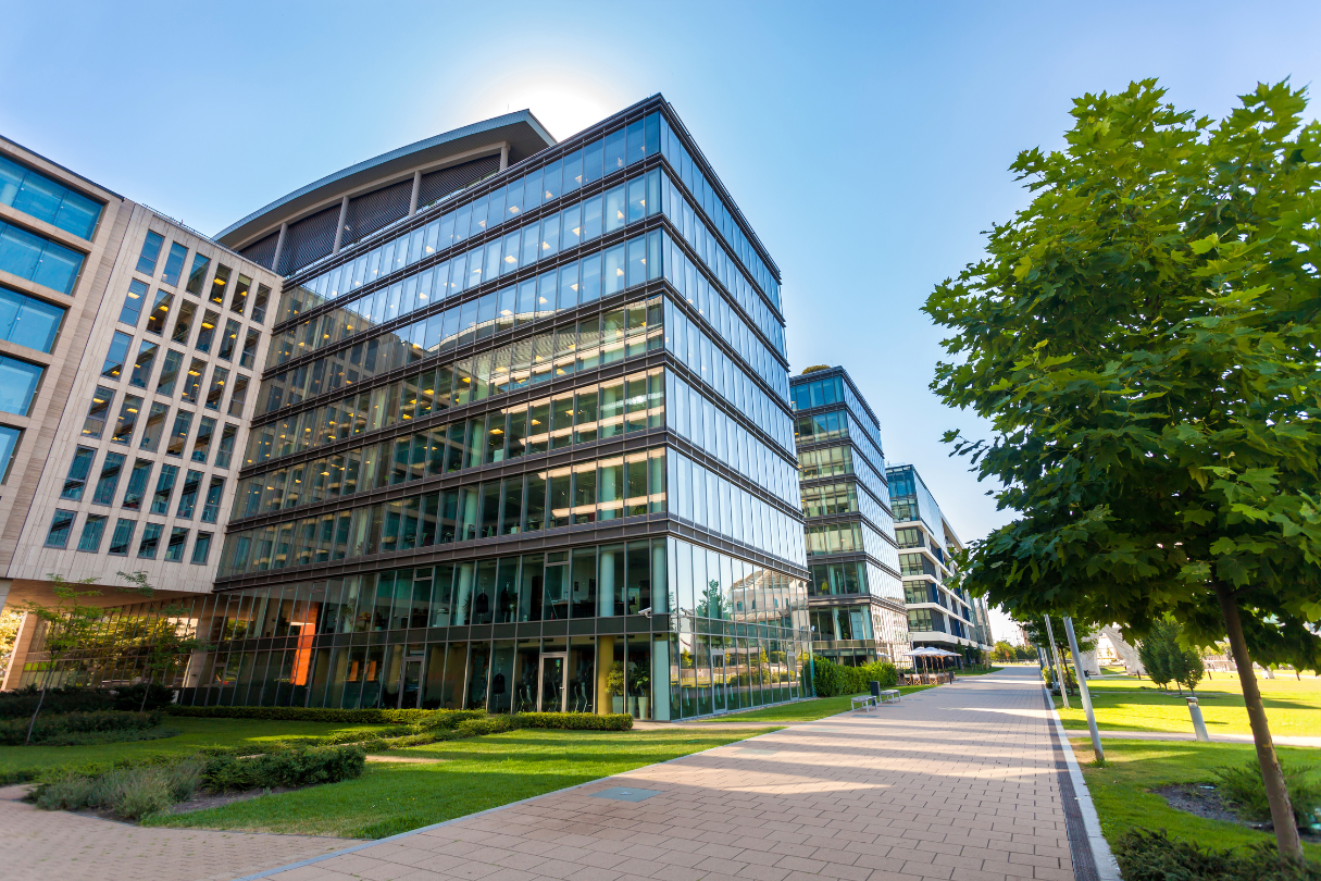 A large building with a lot of windows is surrounded by trees and grass.