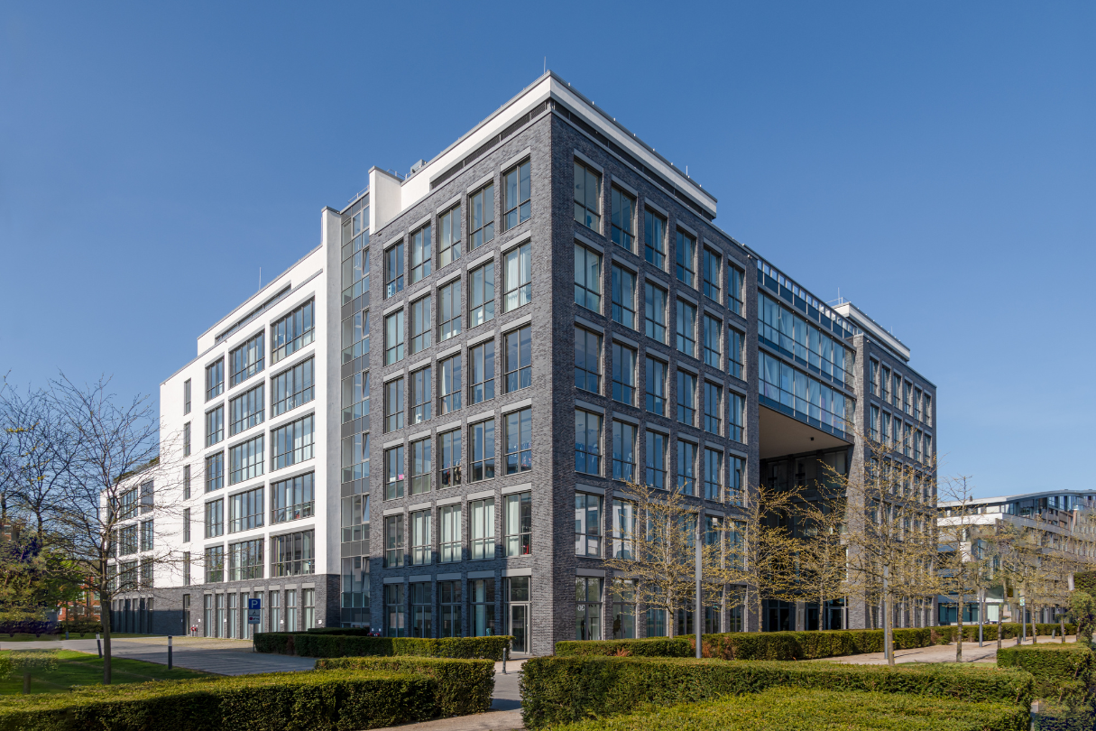 A large building with a lot of windows is surrounded by trees and bushes.