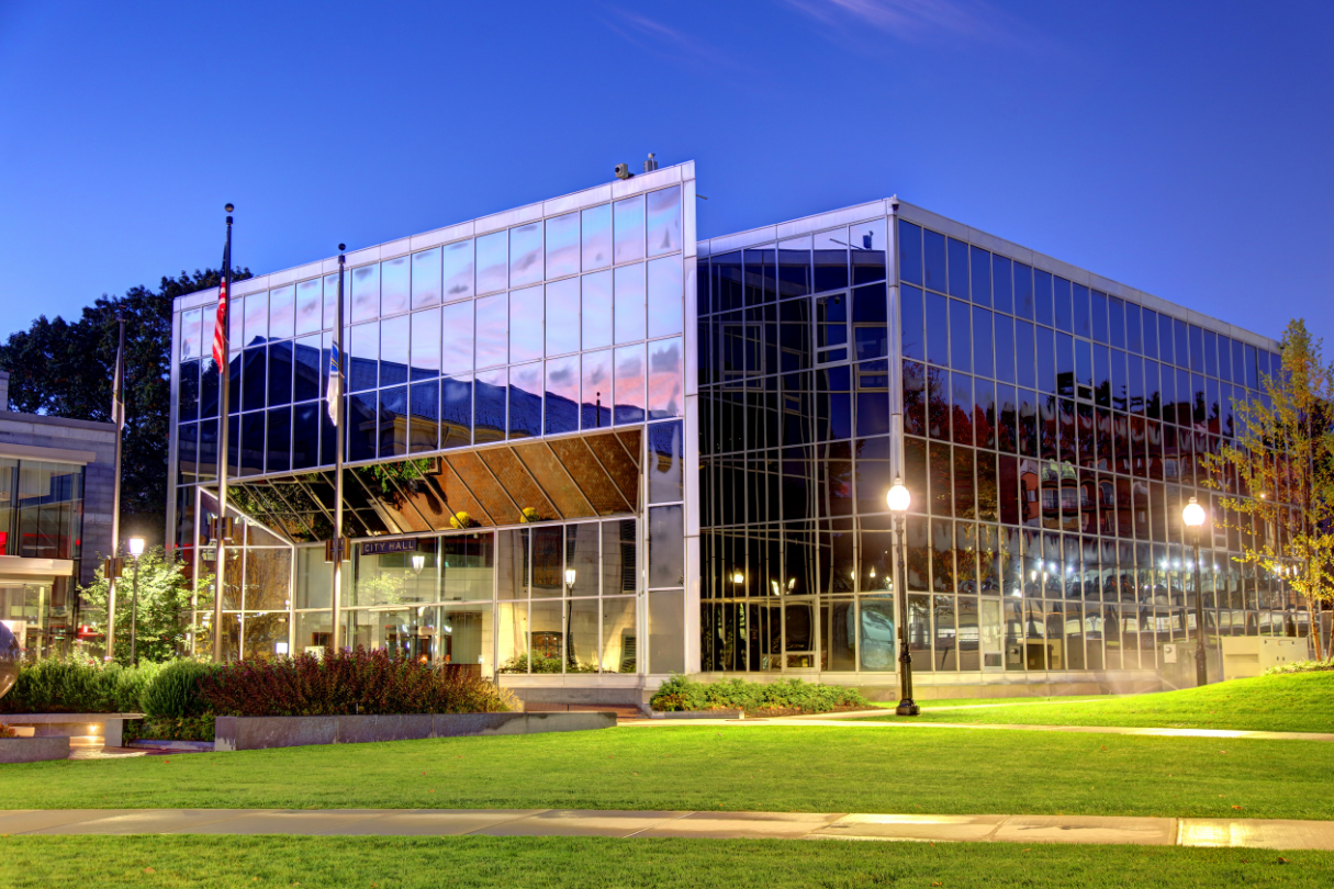 A large glass building with a lot of windows is lit up at night.