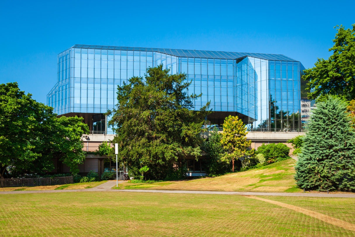 A large building with a lot of windows is surrounded by trees and grass.