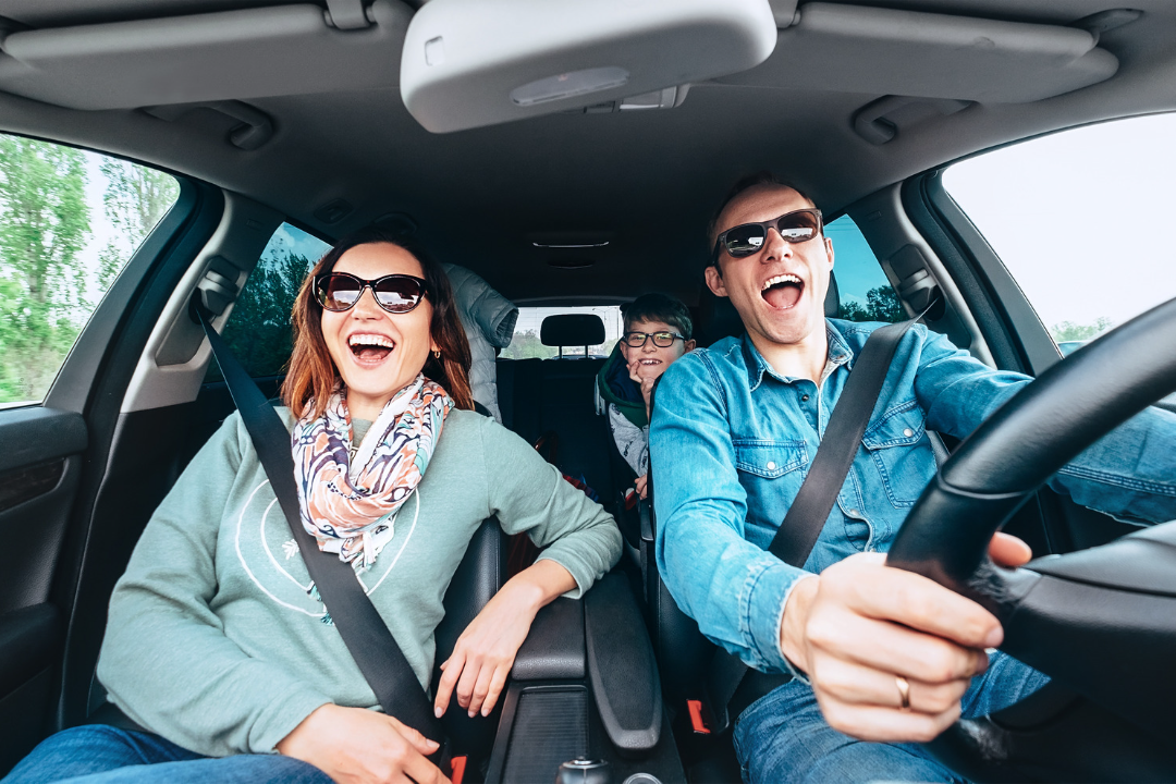 A family is sitting in the back seat of a car.