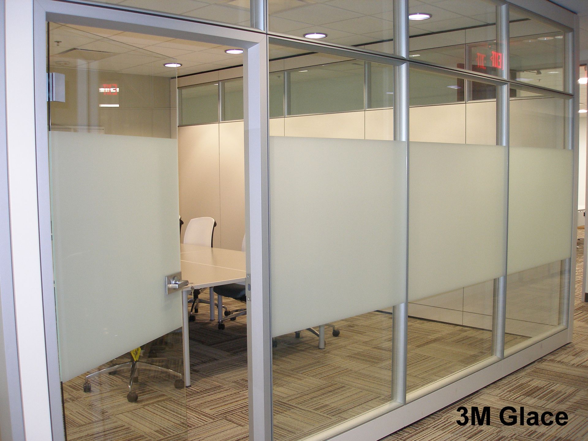 A glass-partitioned office featuring a table and chairs, with privacy film on windows for enhanced confidentiality.