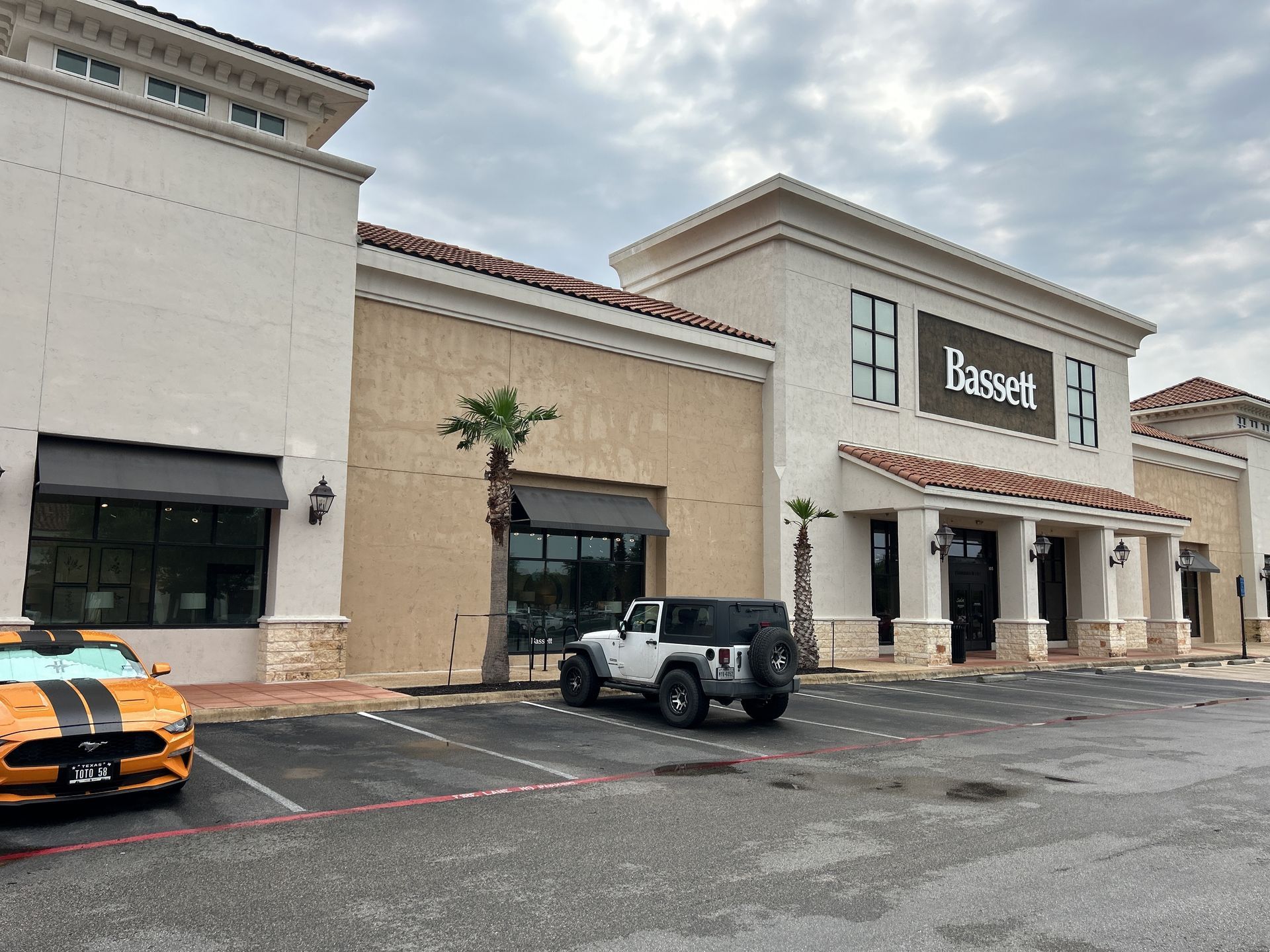 A yellow car is parked in front of a building that says dassel.