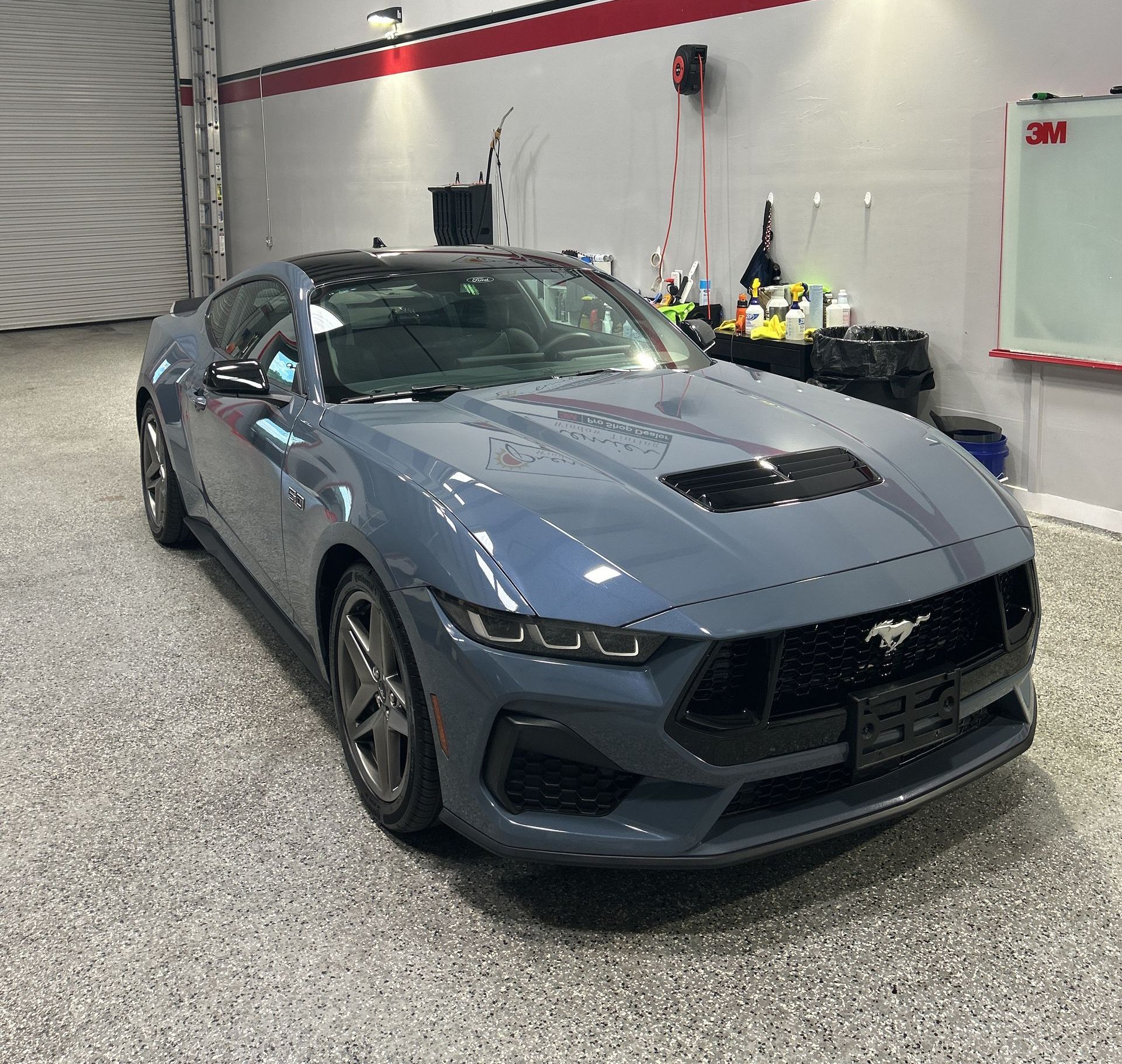 A gray ford mustang is parked in a garage.