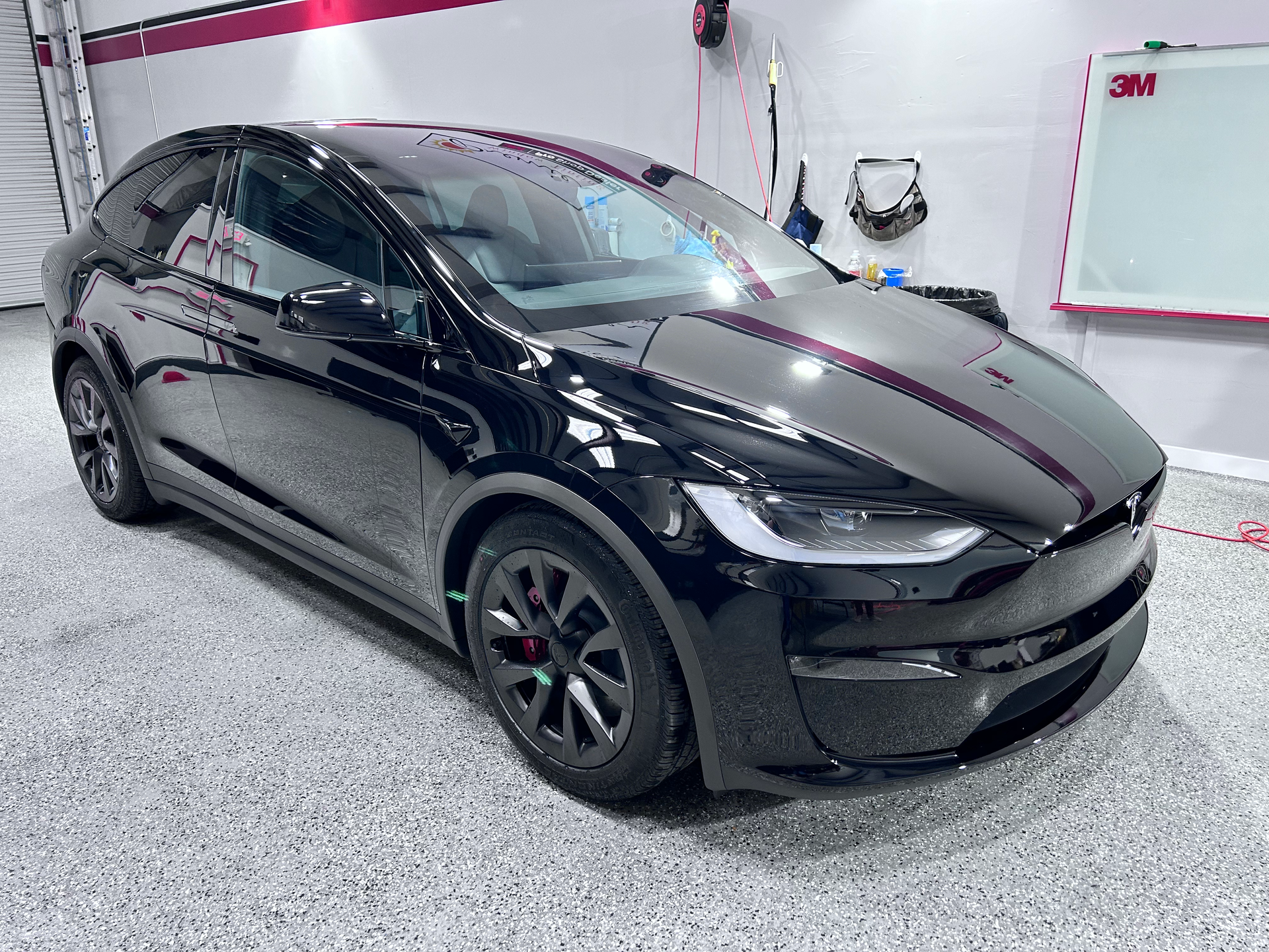 A black tesla model x is parked in a garage.