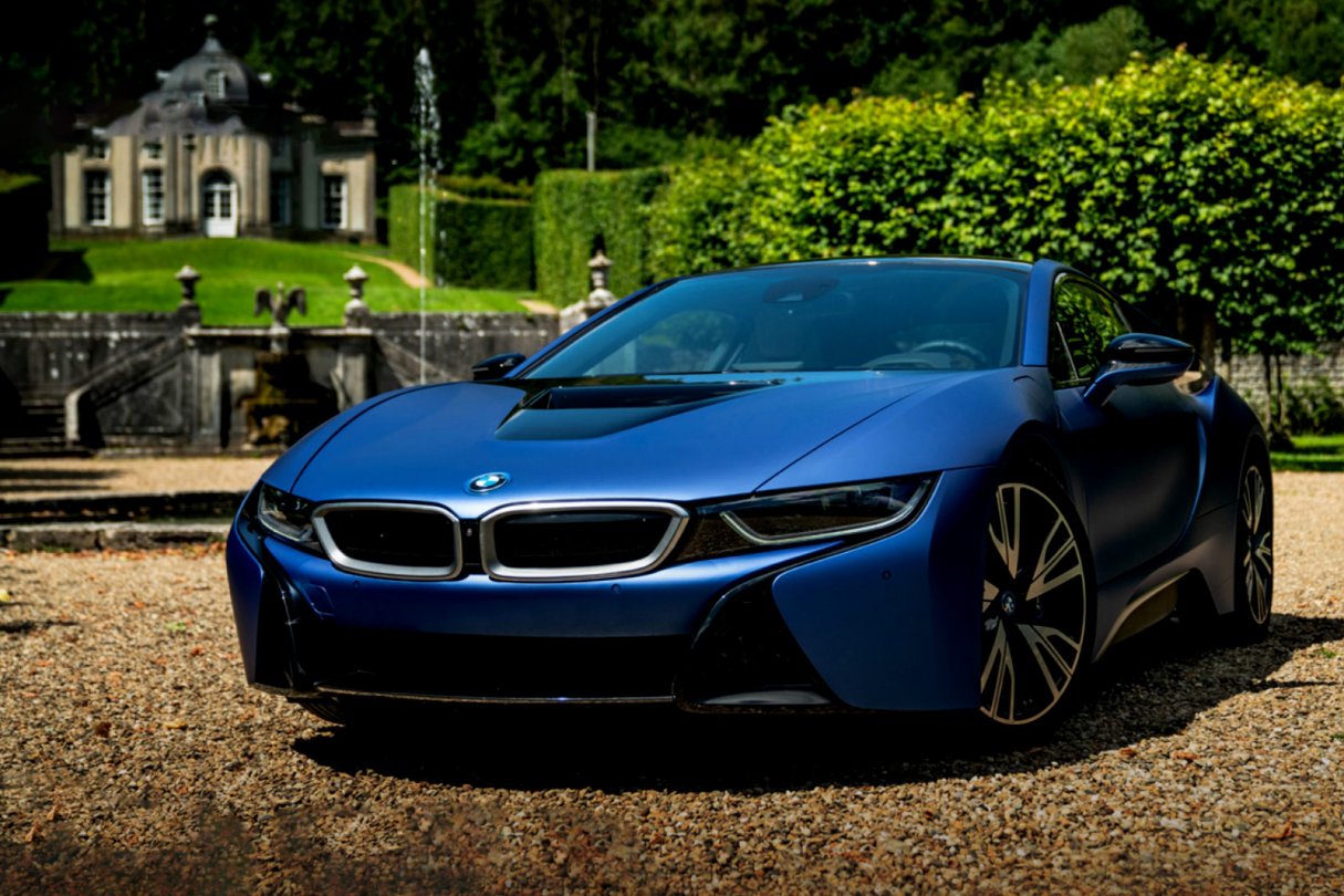 A blue bmw i8 is parked in front of a house.